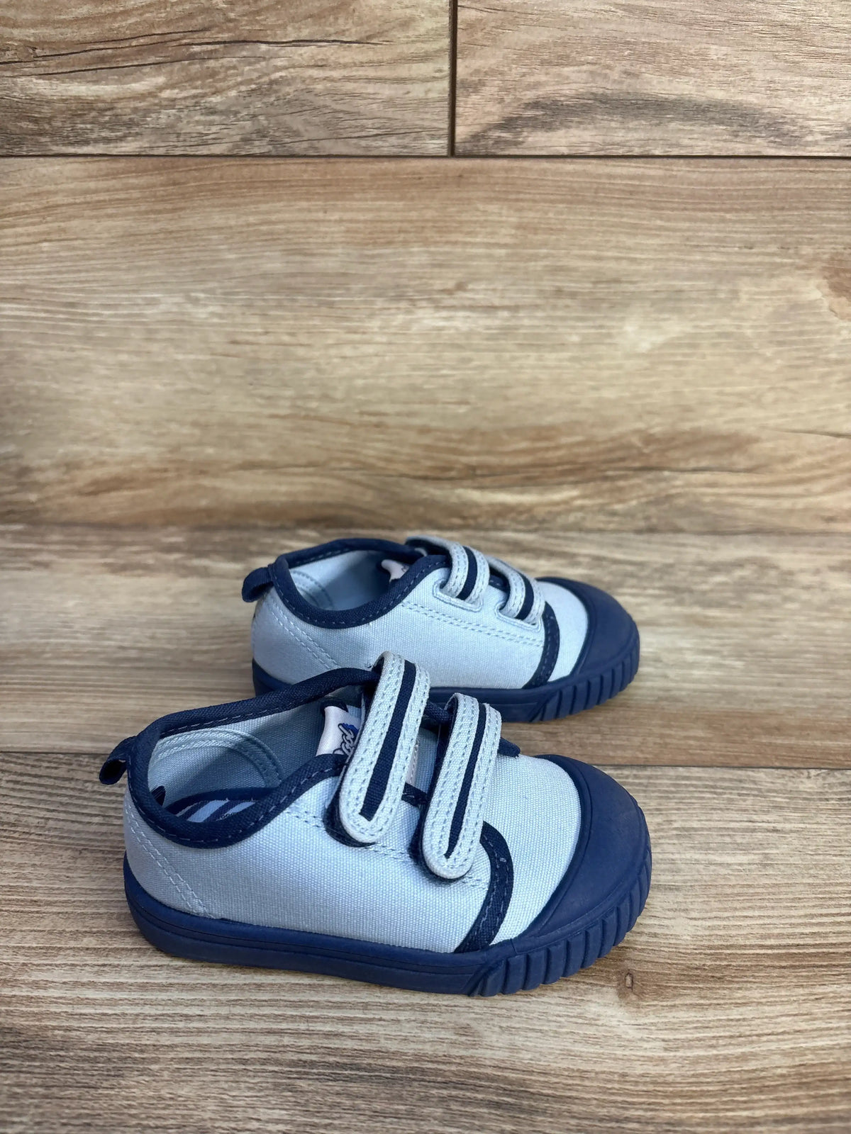 Light blue and navy two strap sneakers for kids by Me n Mommy To Be on a wooden background.