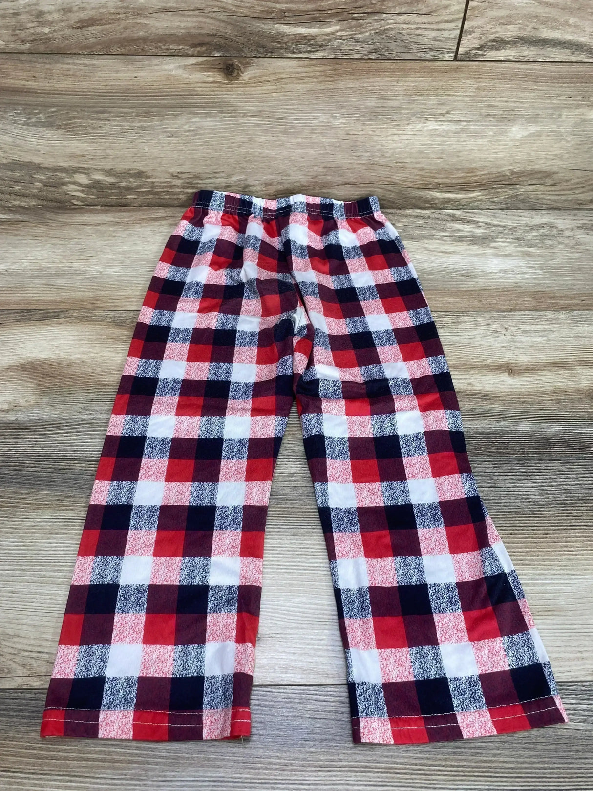 Flat lay of toddler plaid pants size 4T showing red, black and white buffalo check and elastic waistband on wood floor
