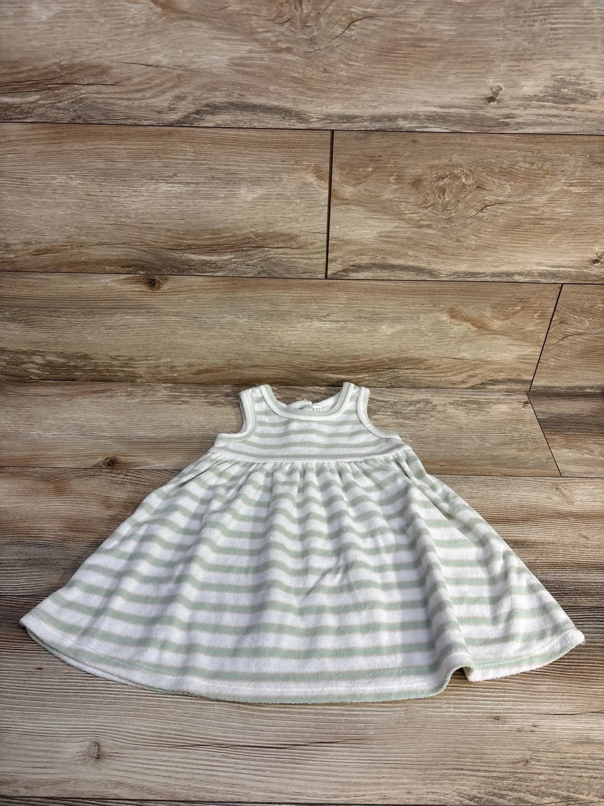 Flat lay of white and pale green striped terry cloth baby dress size 18 months showing sleeveless bodice and gathered skirt on wood background