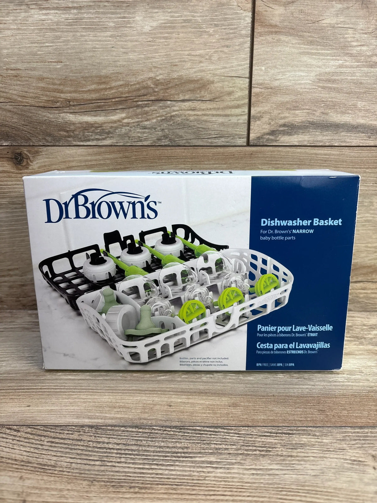 Front view of Dr Brown's boxed dishwasher basket showing white and black basket inserts holding narrow baby bottle parts on wood background