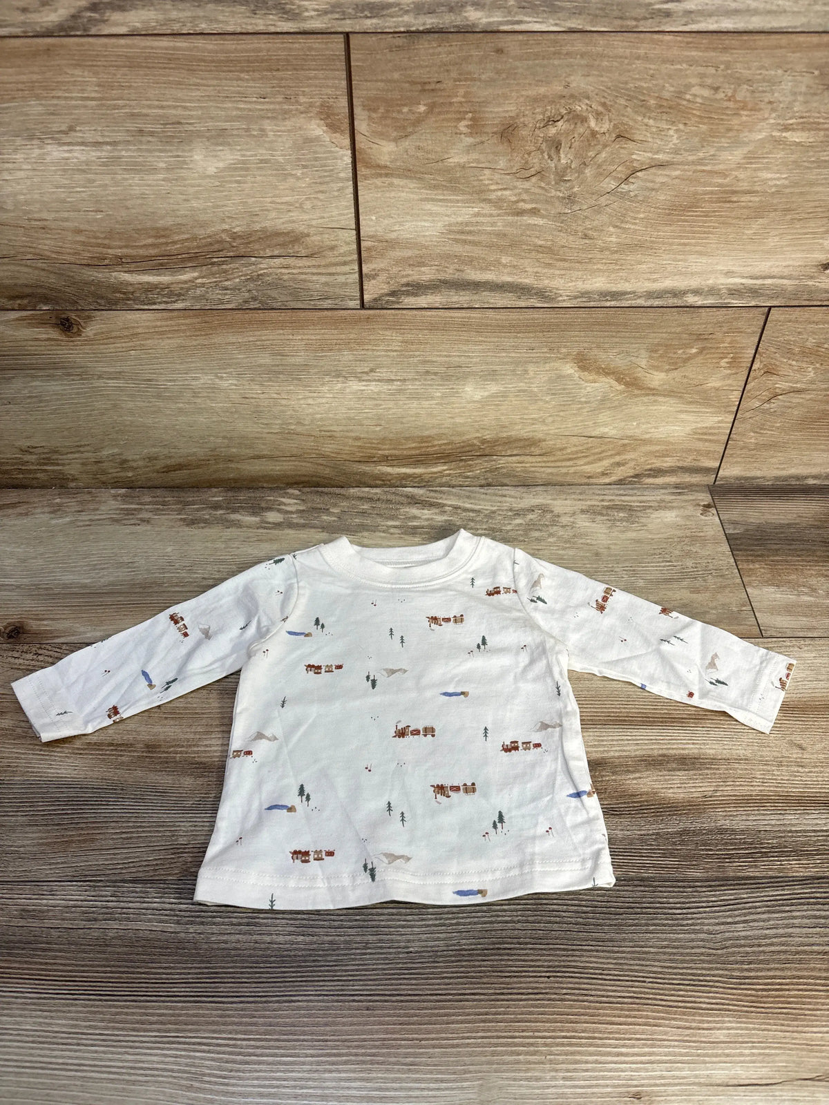 Front view of Just One You white long sleeve shirt size 6 months showcasing train and woodland prints on wood background