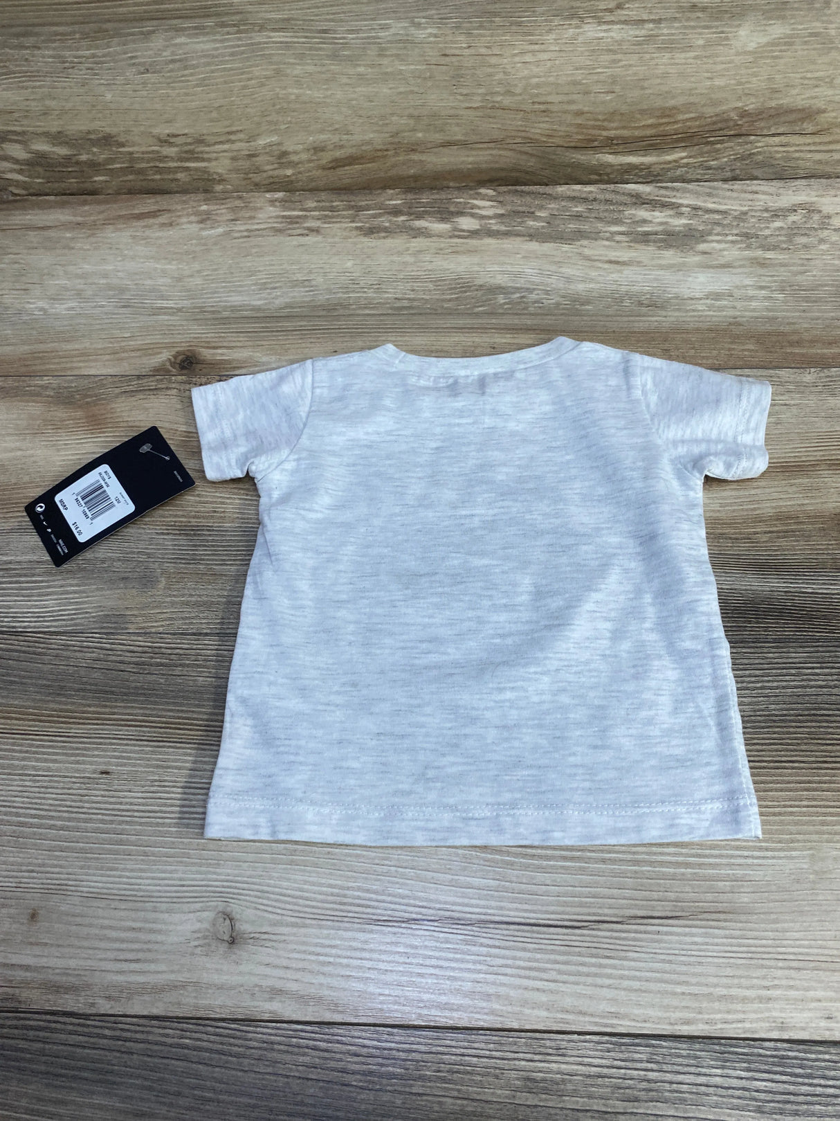 Back view of plain light gray short sleeve toddler t-shirt on wooden surface with price tag attached