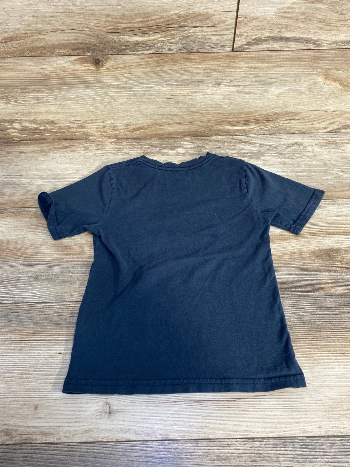 Navy blue short sleeve t-shirt laid flat on wood background