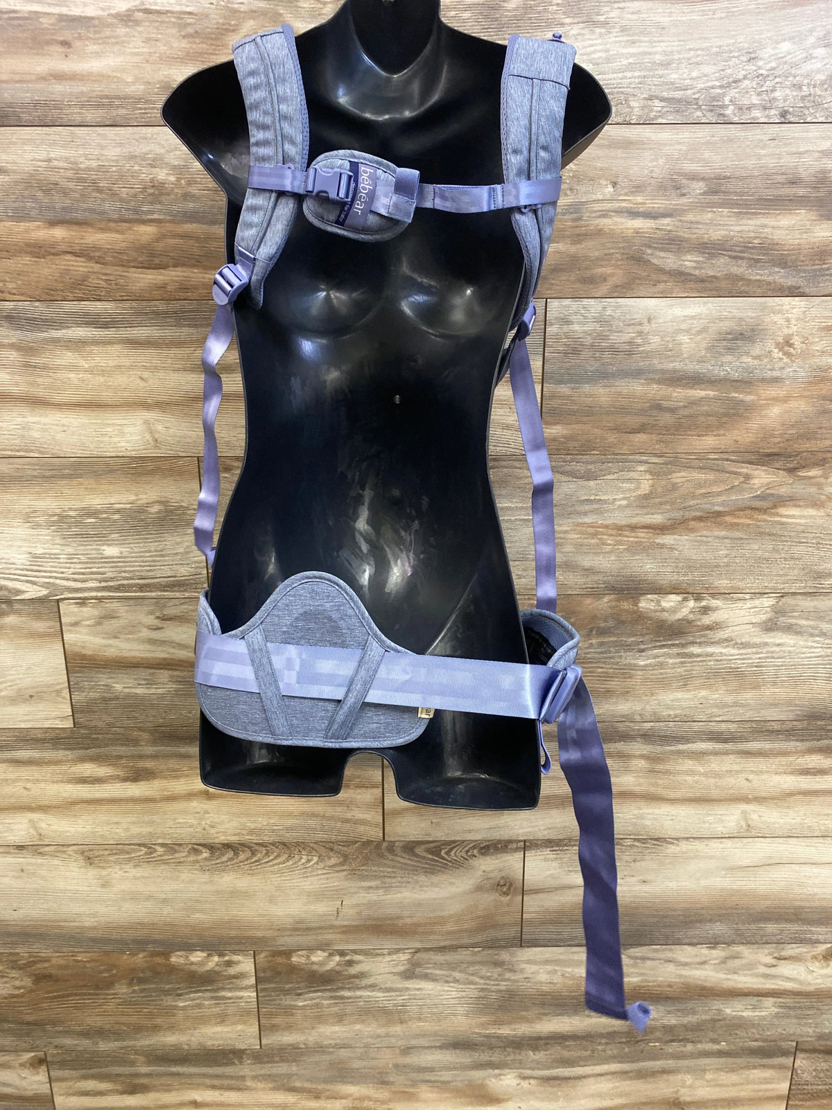 Front view of Bebear 2-in-1 Bebamour hip-seat baby carrier showing padded shoulder straps on black mannequin, wood background