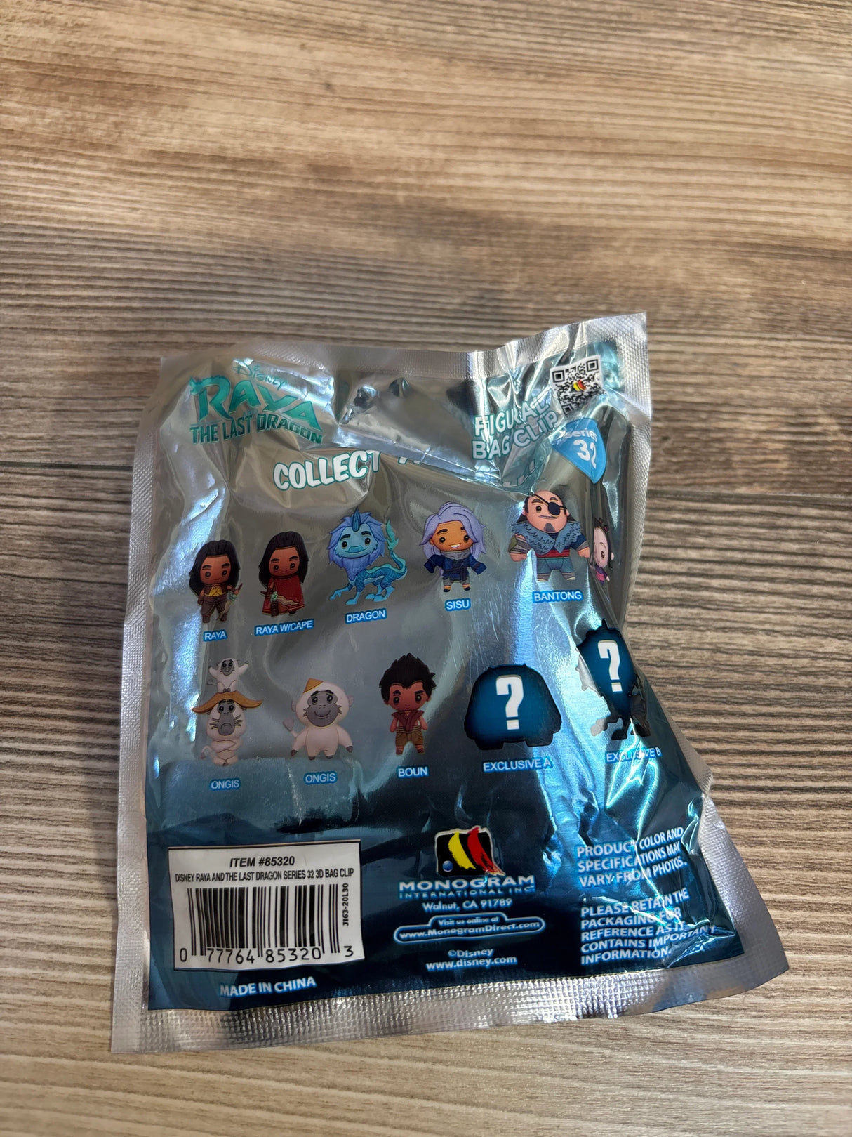 Raya and the Last Dragon figurine bag clip blind bag on wood table, showing collectible characters.