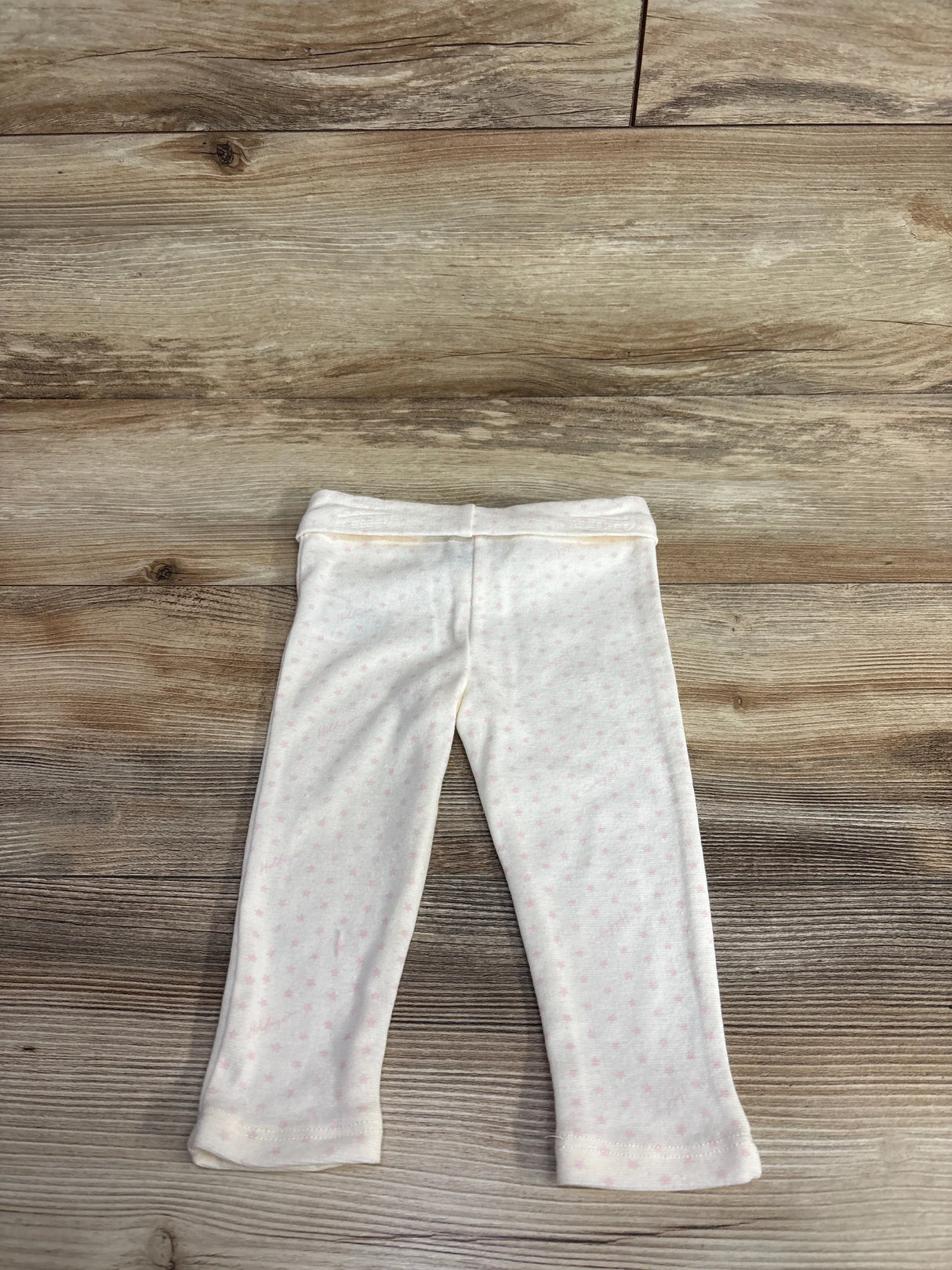 Light pink baby leggings with tiny star pattern on wooden floor
