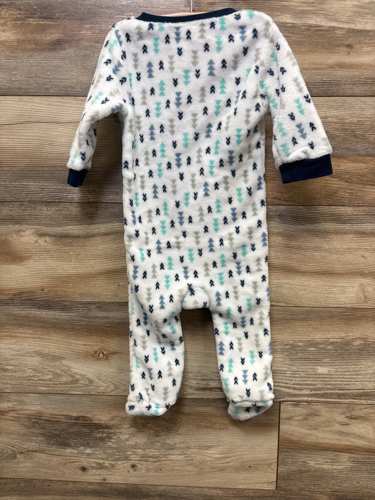 Back view of white plush footed sleep and play, 24 months, showing teal, gray and navy tree pattern and navy cuffs on wood floor