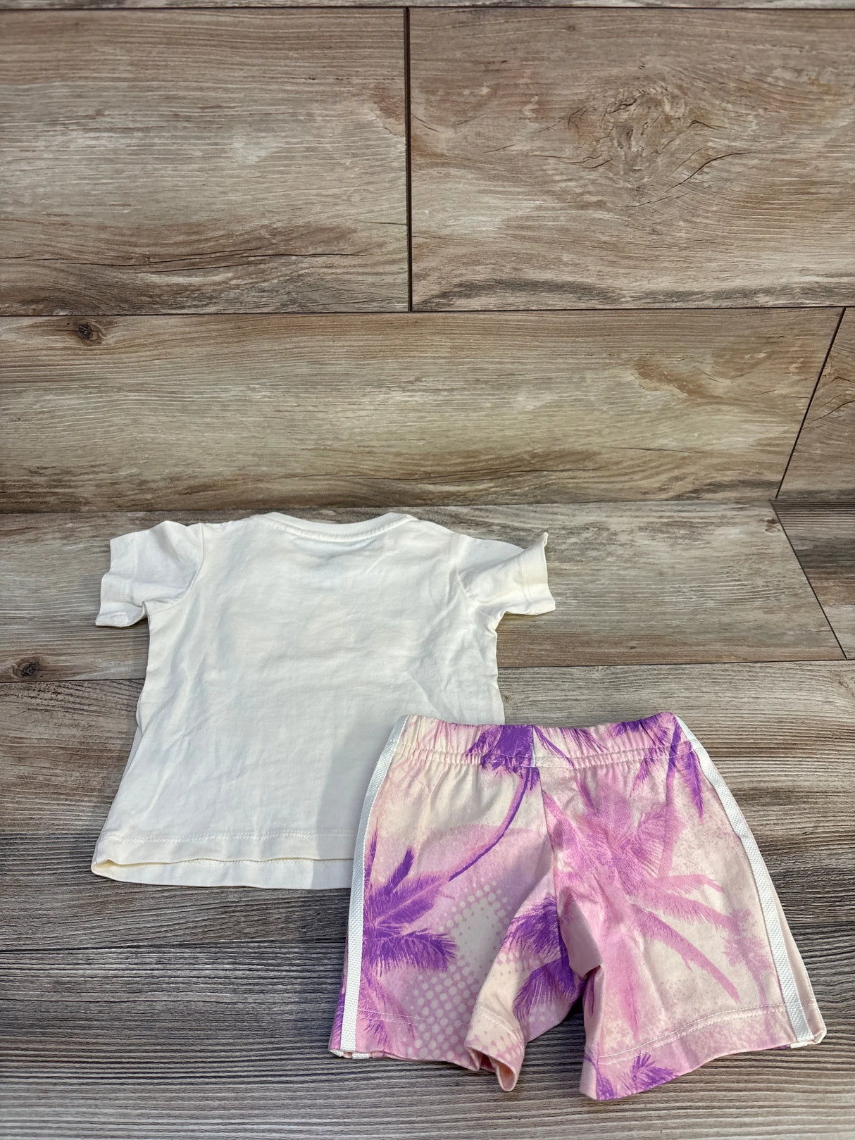 Kids white t-shirt and pink palm tree shorts set on wood floor background