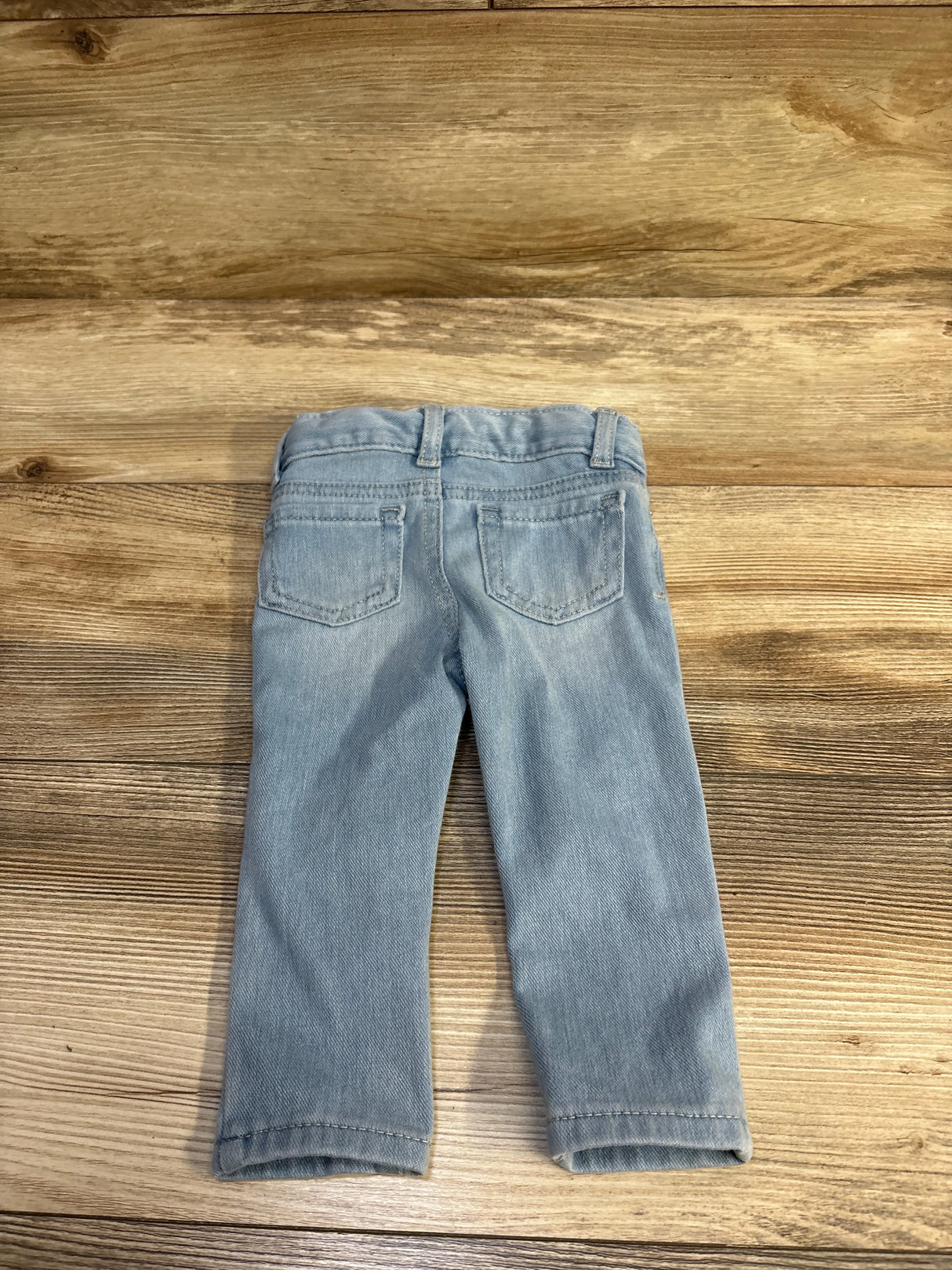 Back view of Cat & Jack light blue toddler jeggings showcasing elastic waistband and back pockets on wood background