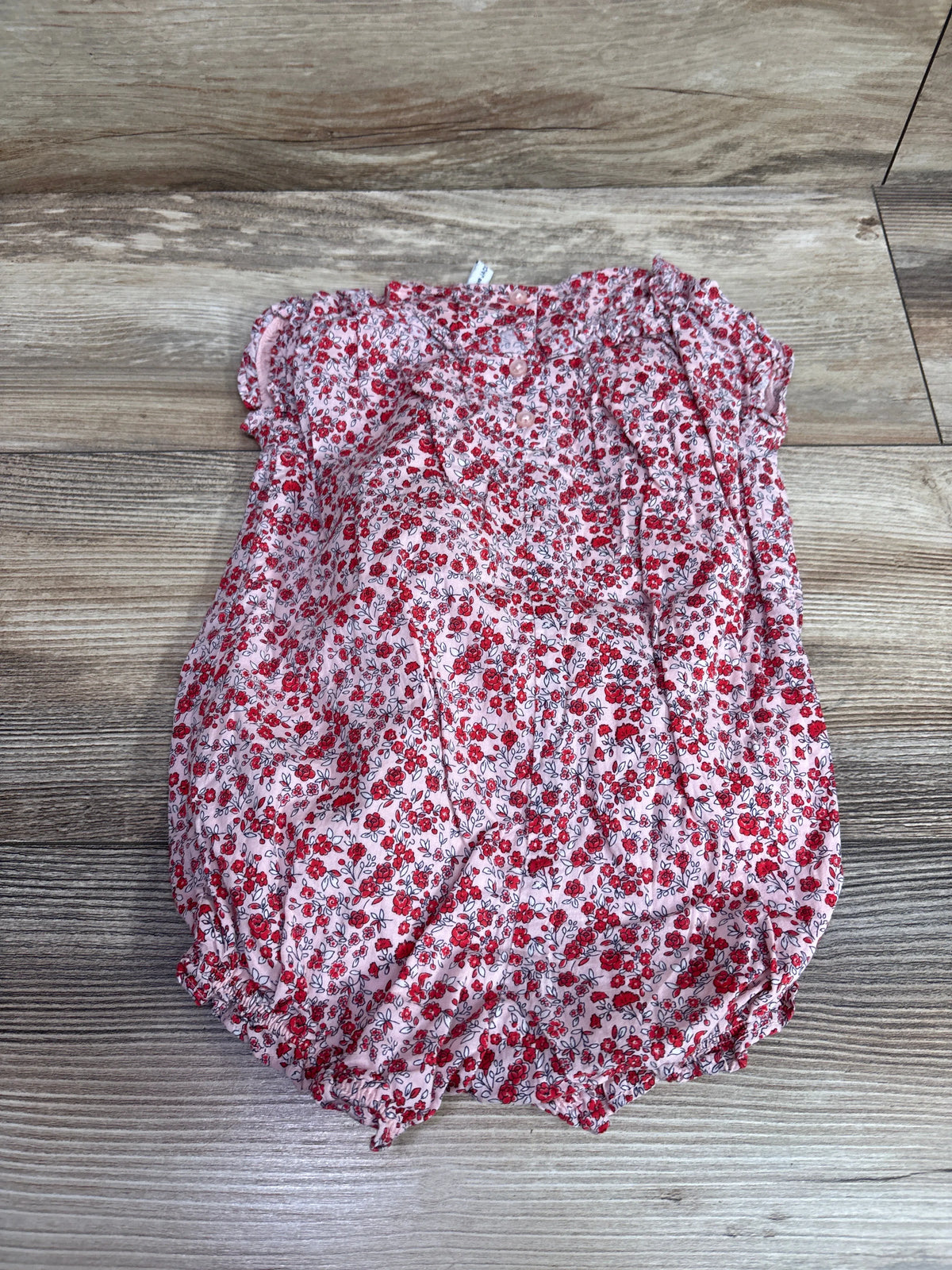 Janie & Jack ditsy floral ruffle romper in pink for babies size 6-12m on a wood background