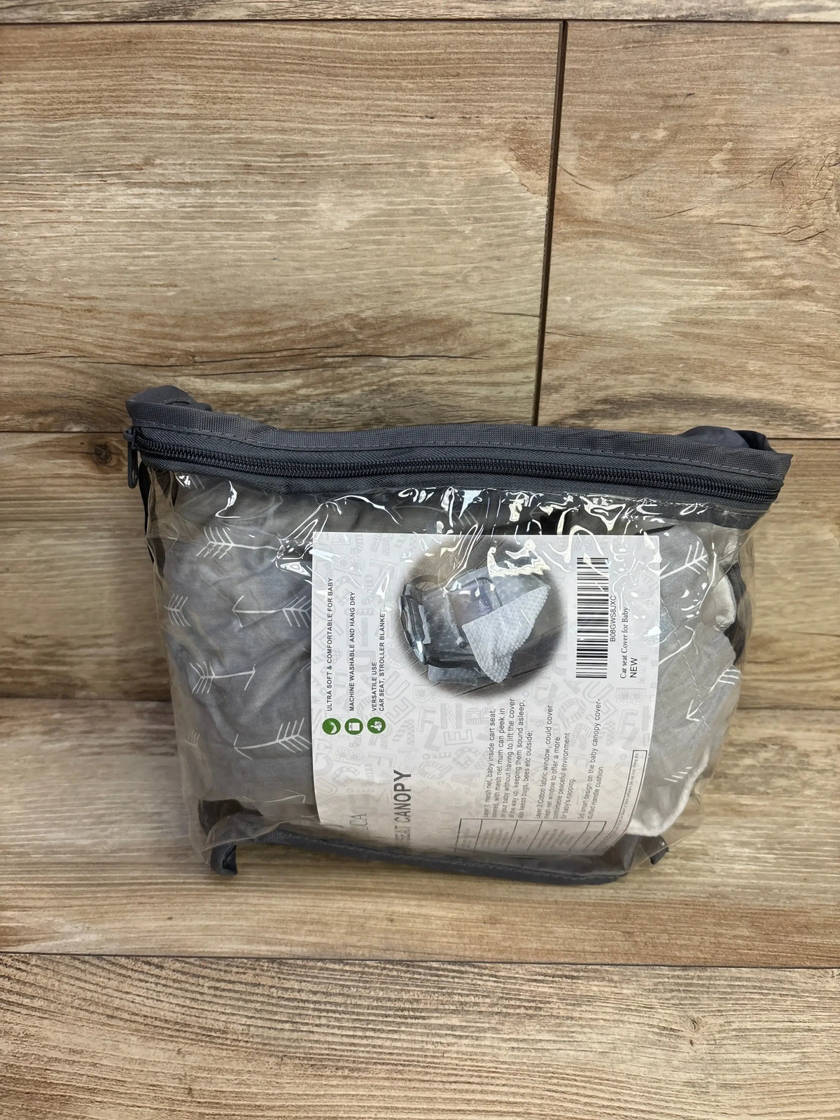 Front view of Icopuca car seat cover packaged in clear zip pouch showing grey fabric with white arrow pattern on wooden background