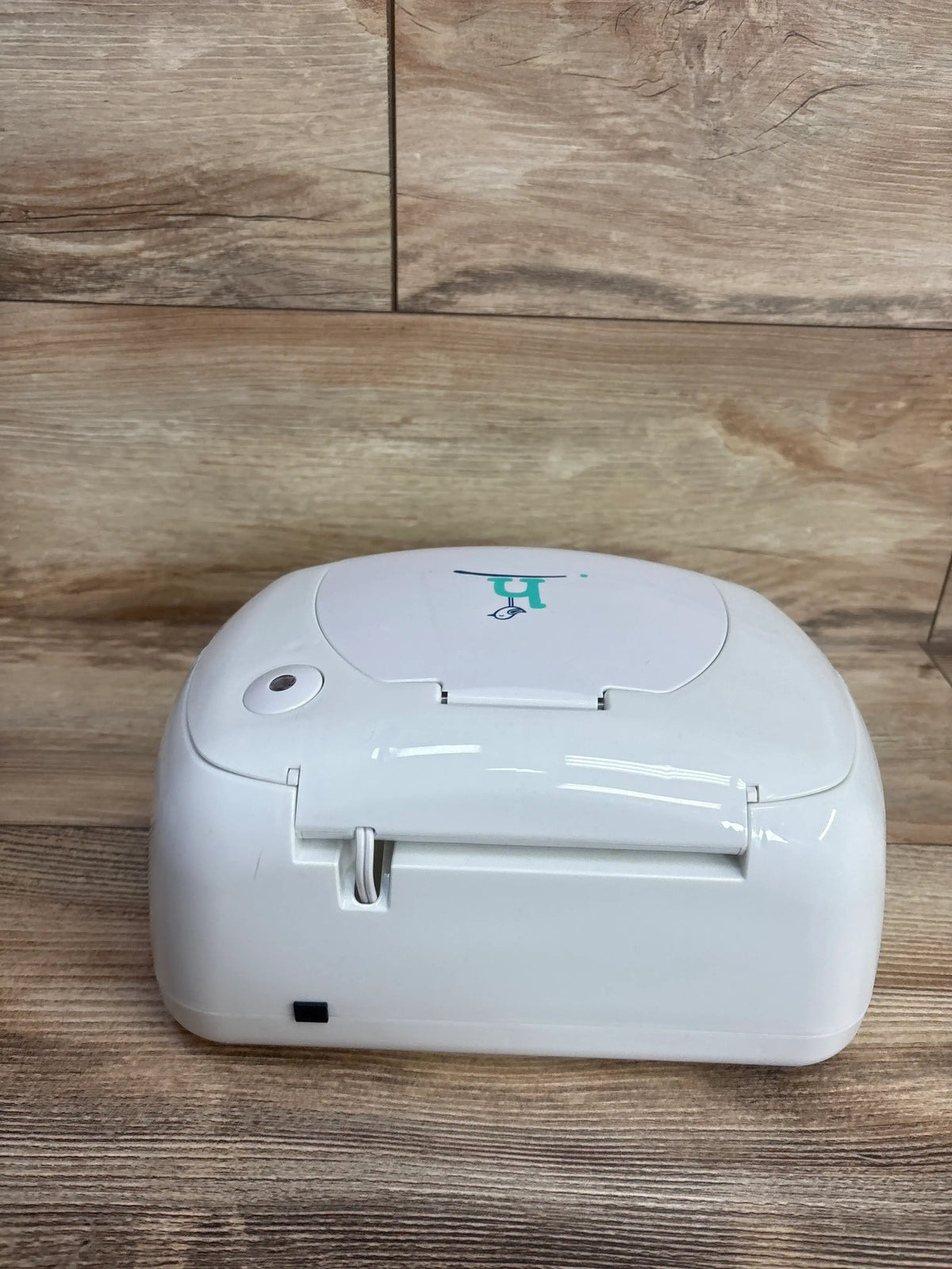White baby wipes dispenser with green logo on wooden surface, children's resale store item