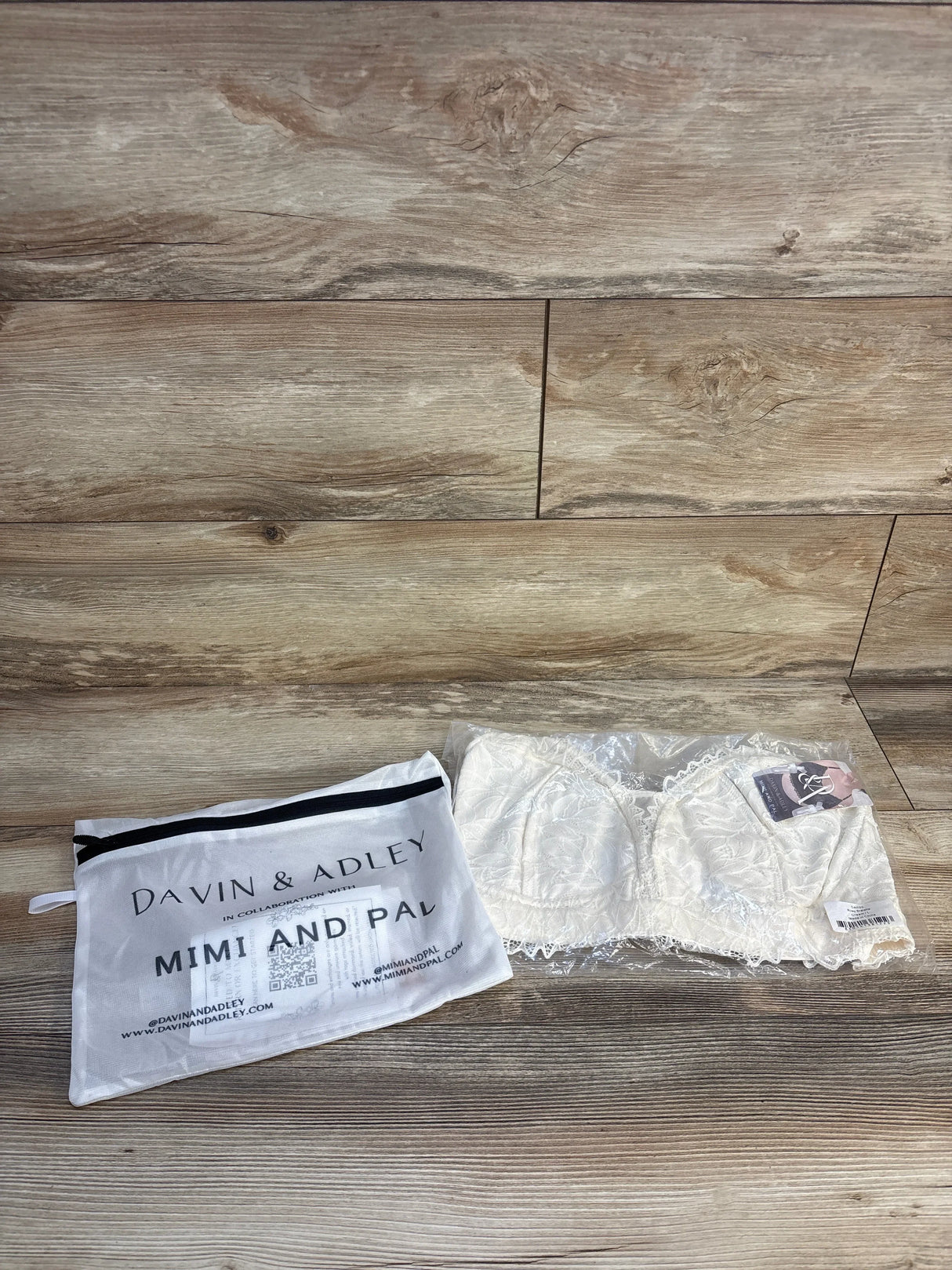 White lace nursing bralette in clear packaging next to Davin & Adley Mimi and Pal storage bag on wood floor