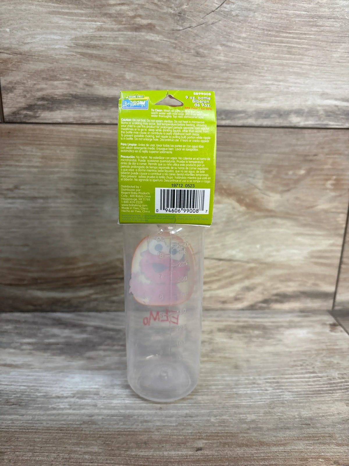 Upright packaged Sesame Street 9-ounce baby bottle with medium flow silicone nipple and measurement markings on wood-look surface