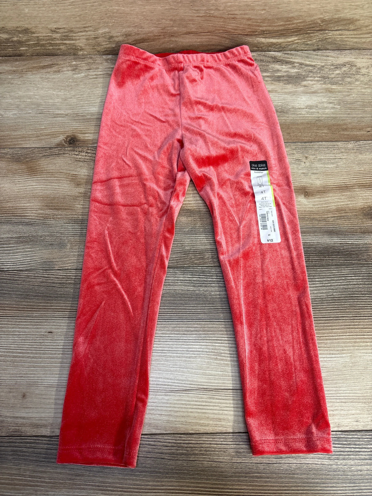 Red velvet toddler leggings with tag on wooden floor