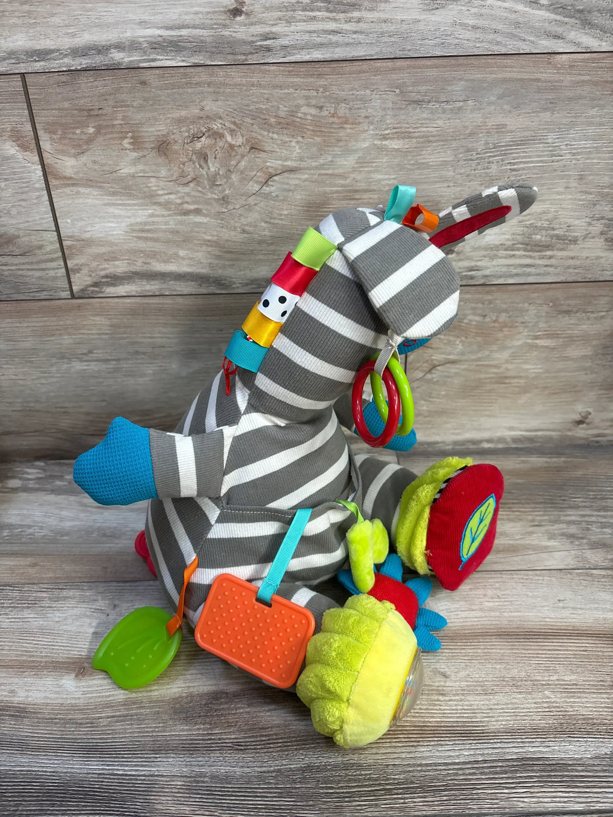 Rear three-quarter view of Dolce Zeddy The Zebra Activity Plush showcasing colorful sensory attachments