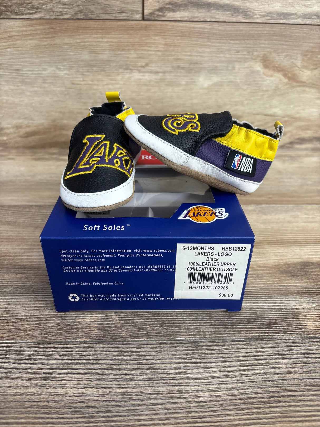 Baby soft sole shoes in black, purple, and yellow with Los Angeles Lakers and NBA logos on box
