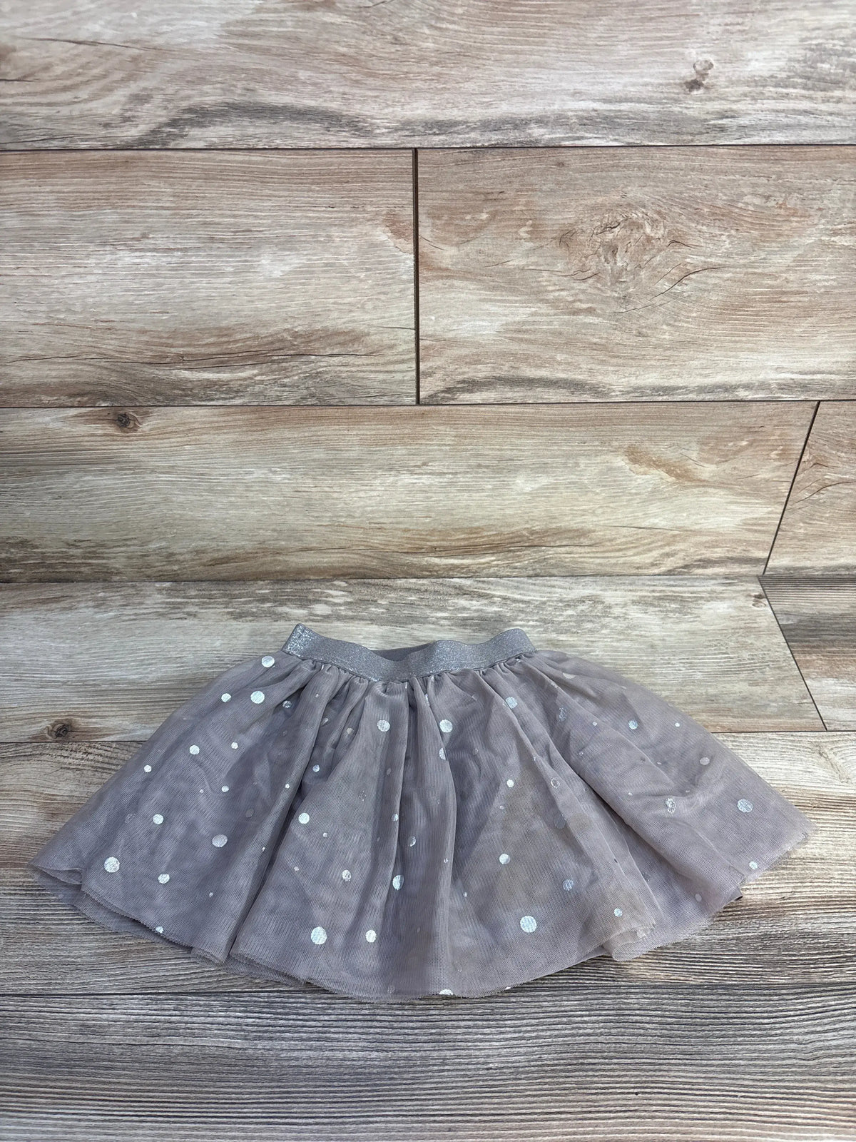 Front view of H&M brown polka dot tulle skirt in size 2T showcasing gathered ruffles and elasticized waistband on wood flooring