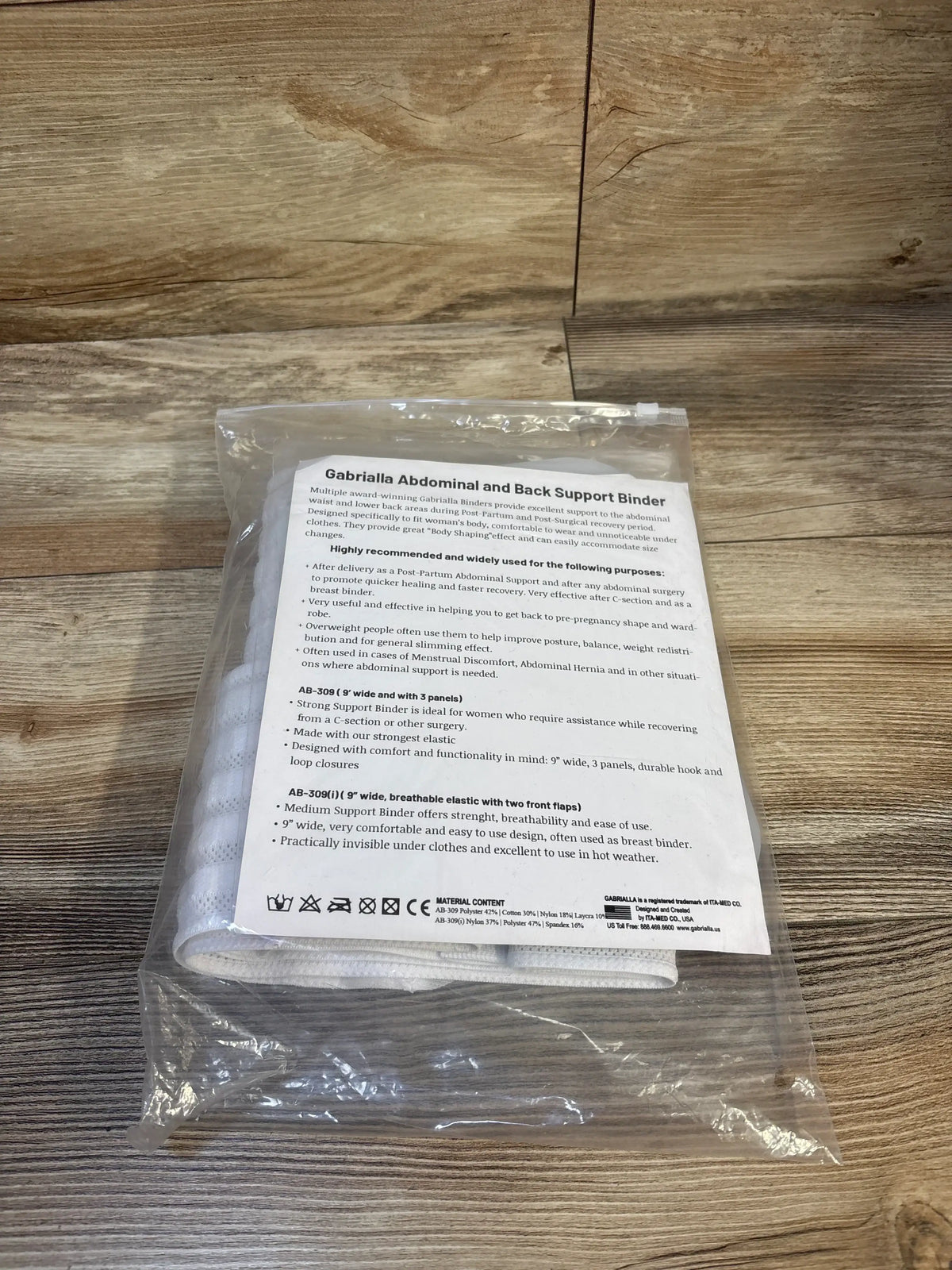 Gabriella abdominal and back support binder in clear packaging on wood surface, postpartum belly wrap.