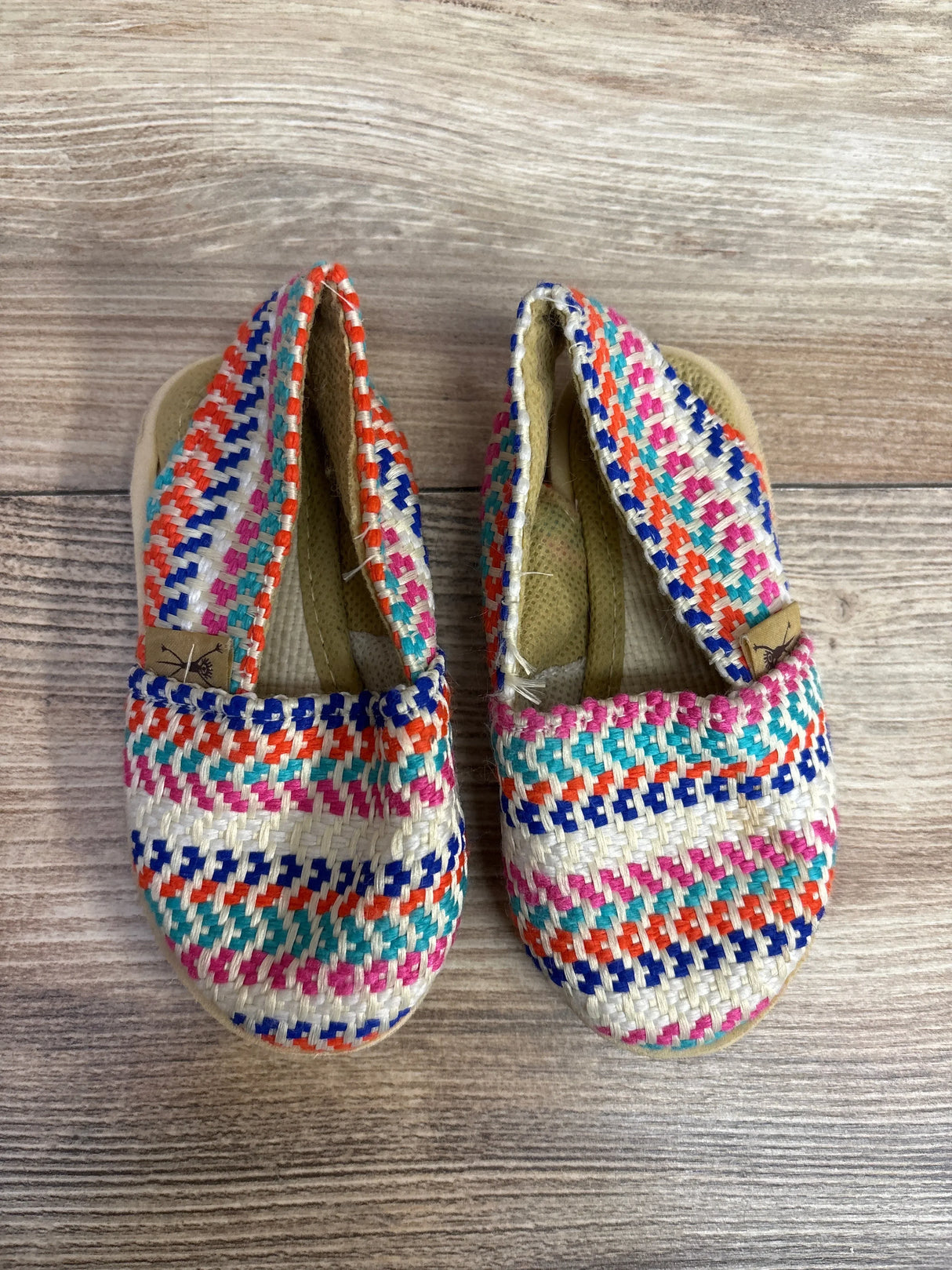 Children's woven fabric slip-on shoes with colorful stripes on wood floor