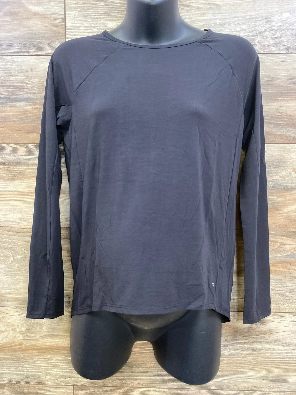 Front of black maternity long-sleeve shirt on torso mannequin with crew neck and raglan sleeves against wood background