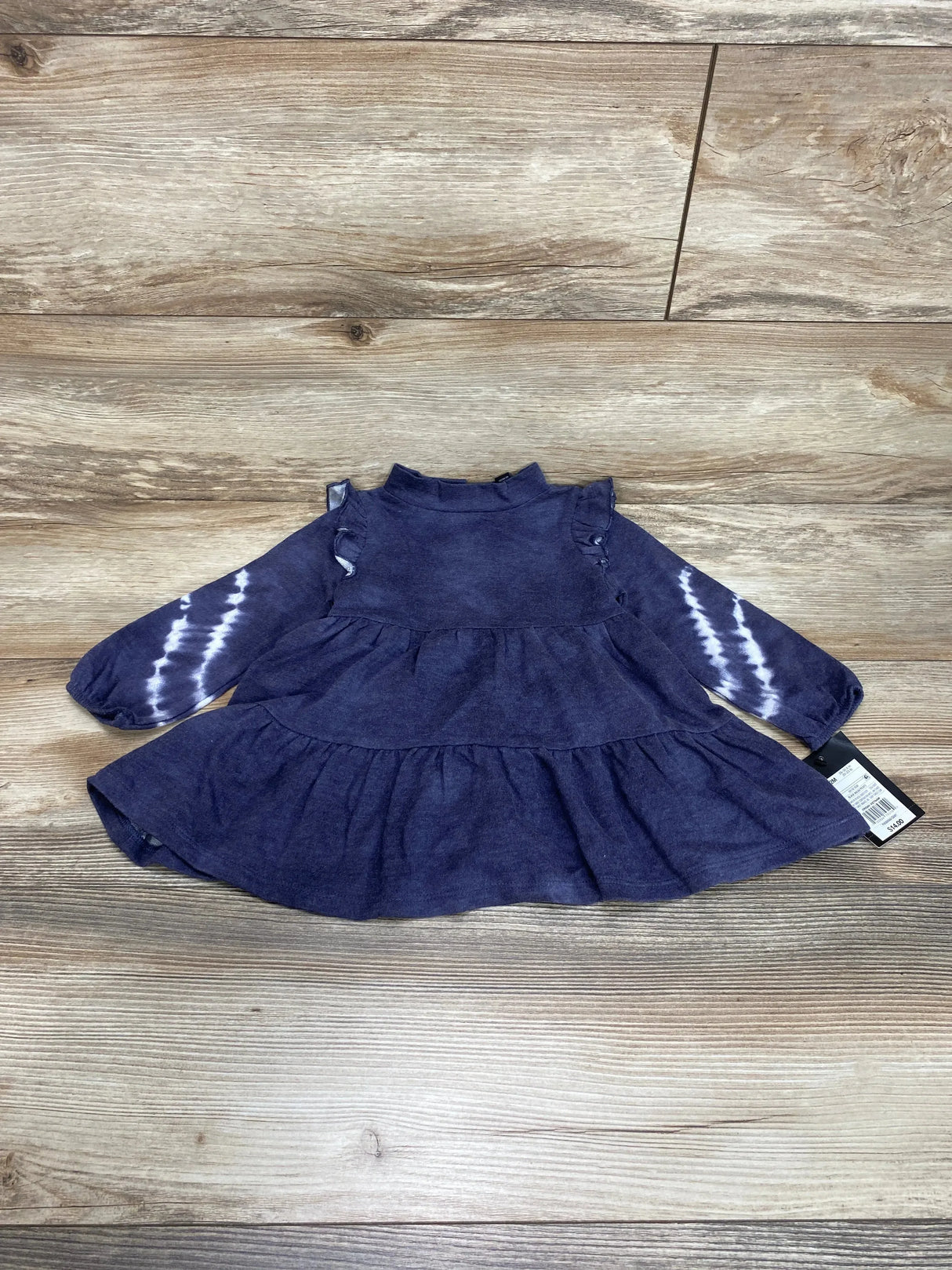 Flat-lay of Art Class black wash 2pc dress 12m showcasing ruffle shoulders and tie-dye long sleeves on wood background