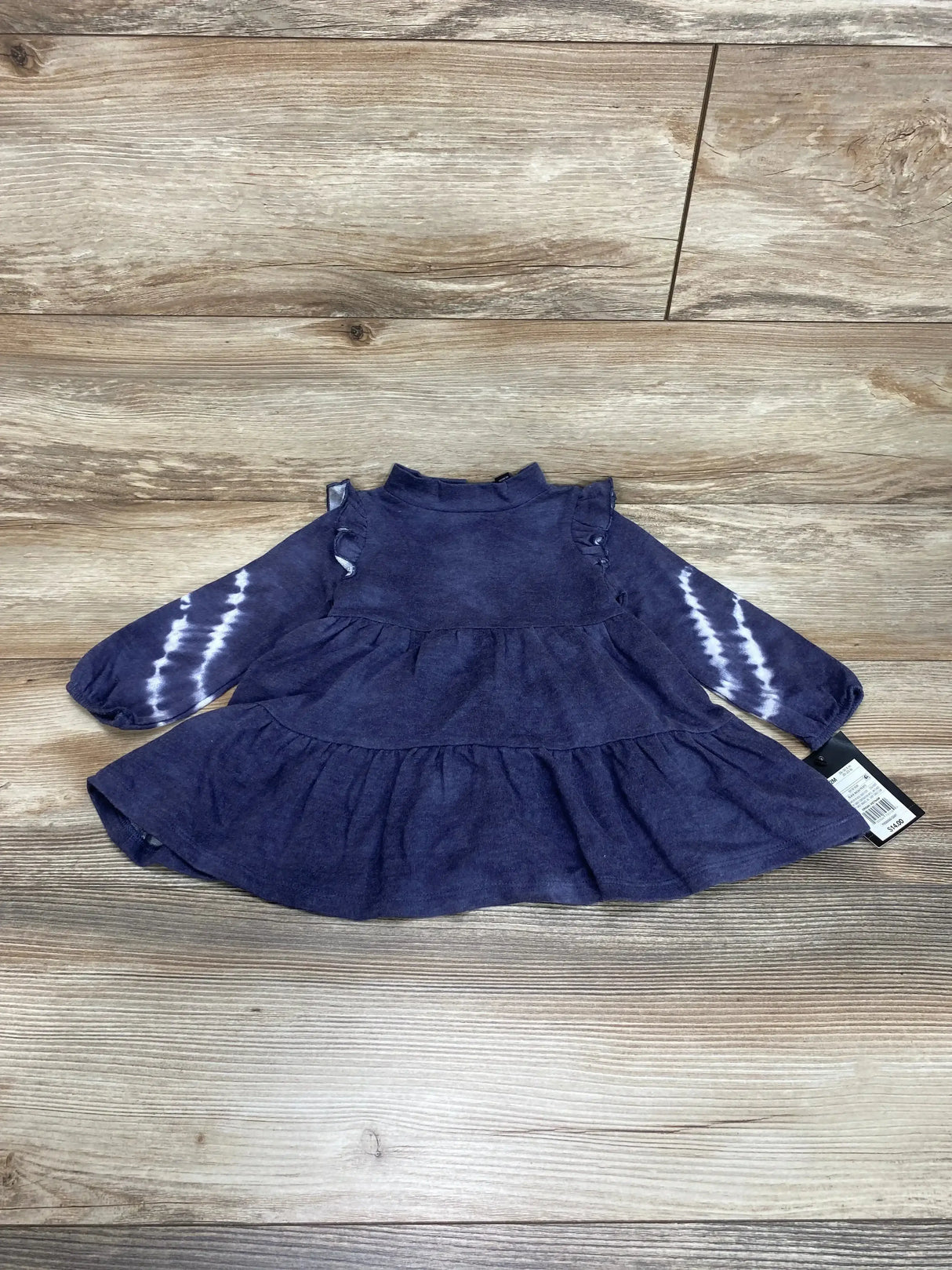 Flat-lay of Art Class black wash 2pc dress 12m showcasing ruffle shoulders and tie-dye long sleeves on wood background