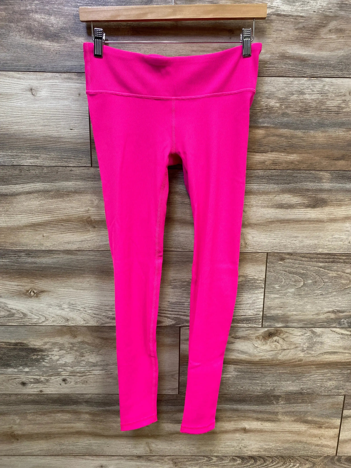 Front view of Gap Fit pink maternity leggings showcasing under belly rib waistband and slim full-length legs against wooden plank background