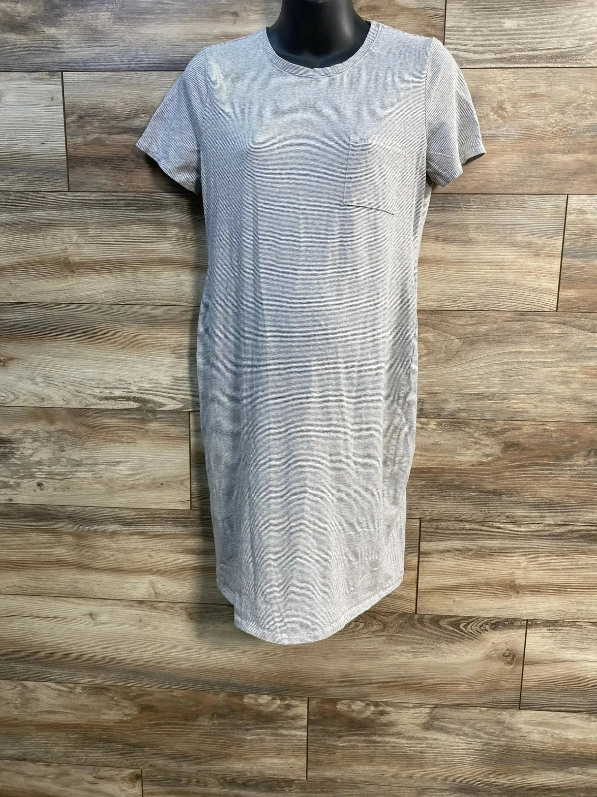 Front view of A Pea In The Pod grey striped maternity dress showcasing short sleeves and chest pocket on wood plank background