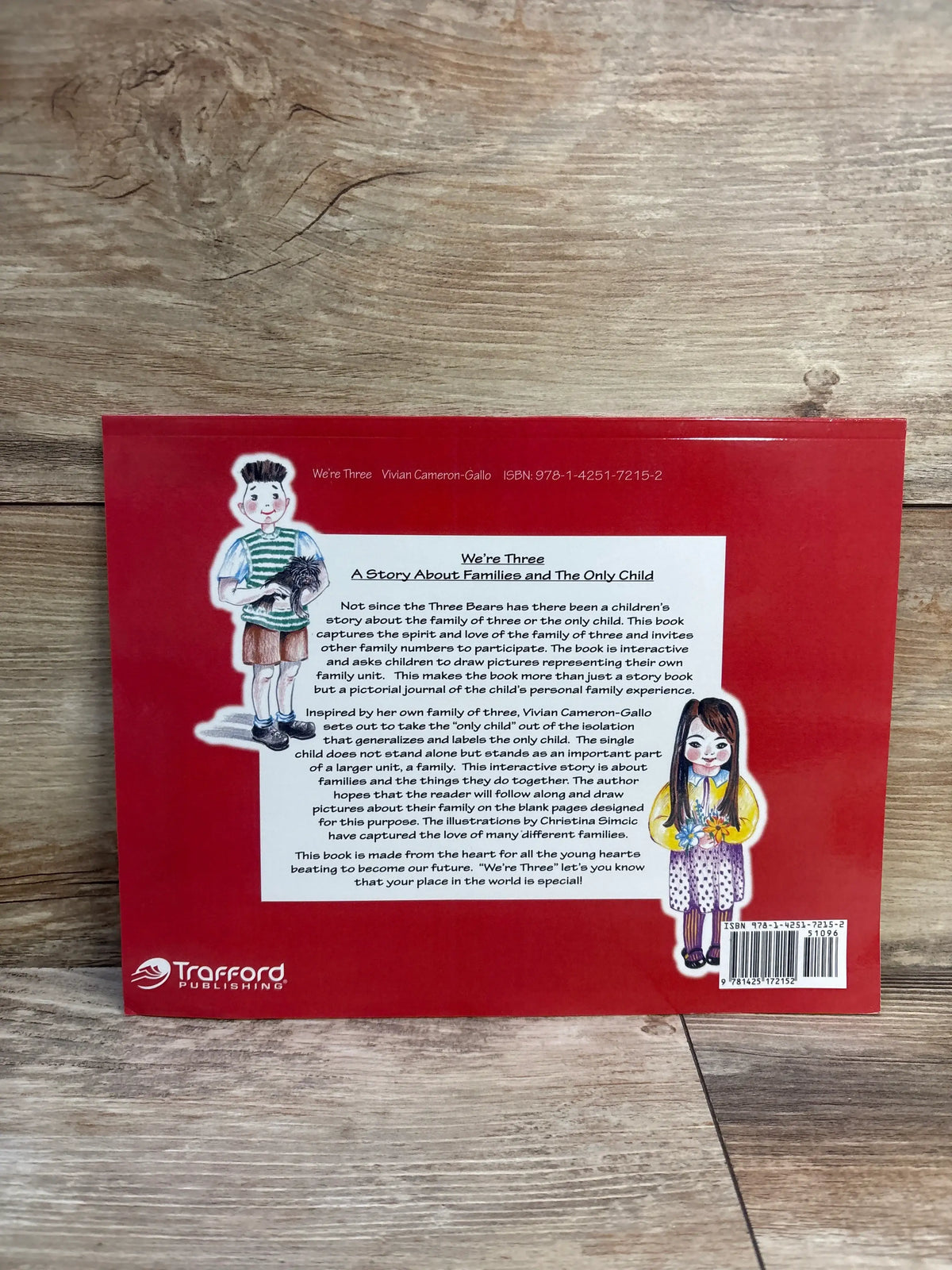 Back cover of We’re Three paperback book showcasing an interactive family of three story on a wood surface