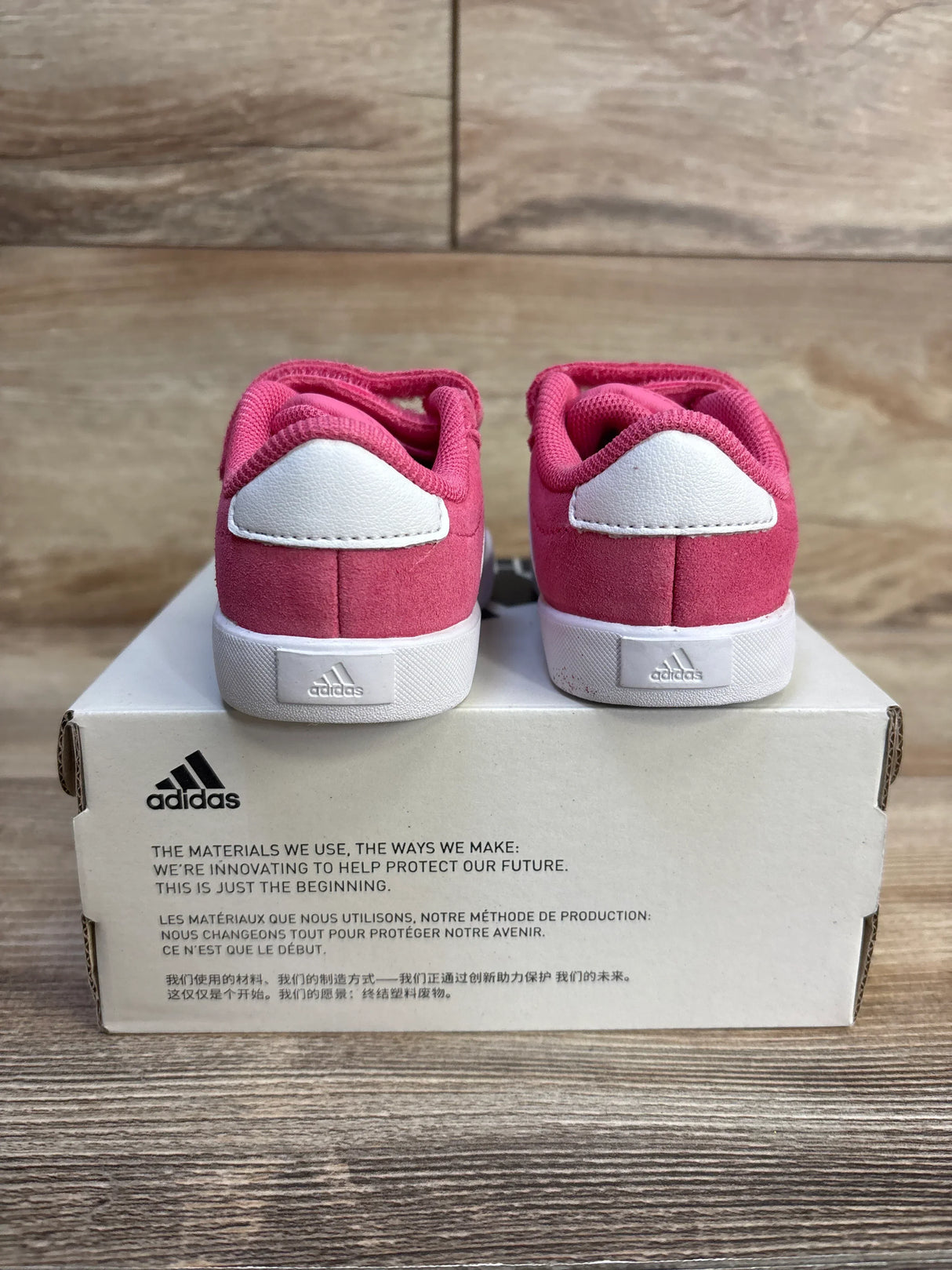 Pink Adidas baby sneakers with white soles, displayed on box, ideal for toddler footwear