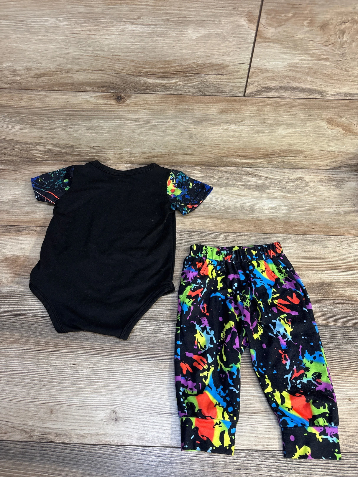 Black baby onesie with rainbow paint splatter sleeves and matching pants, kids clothing set