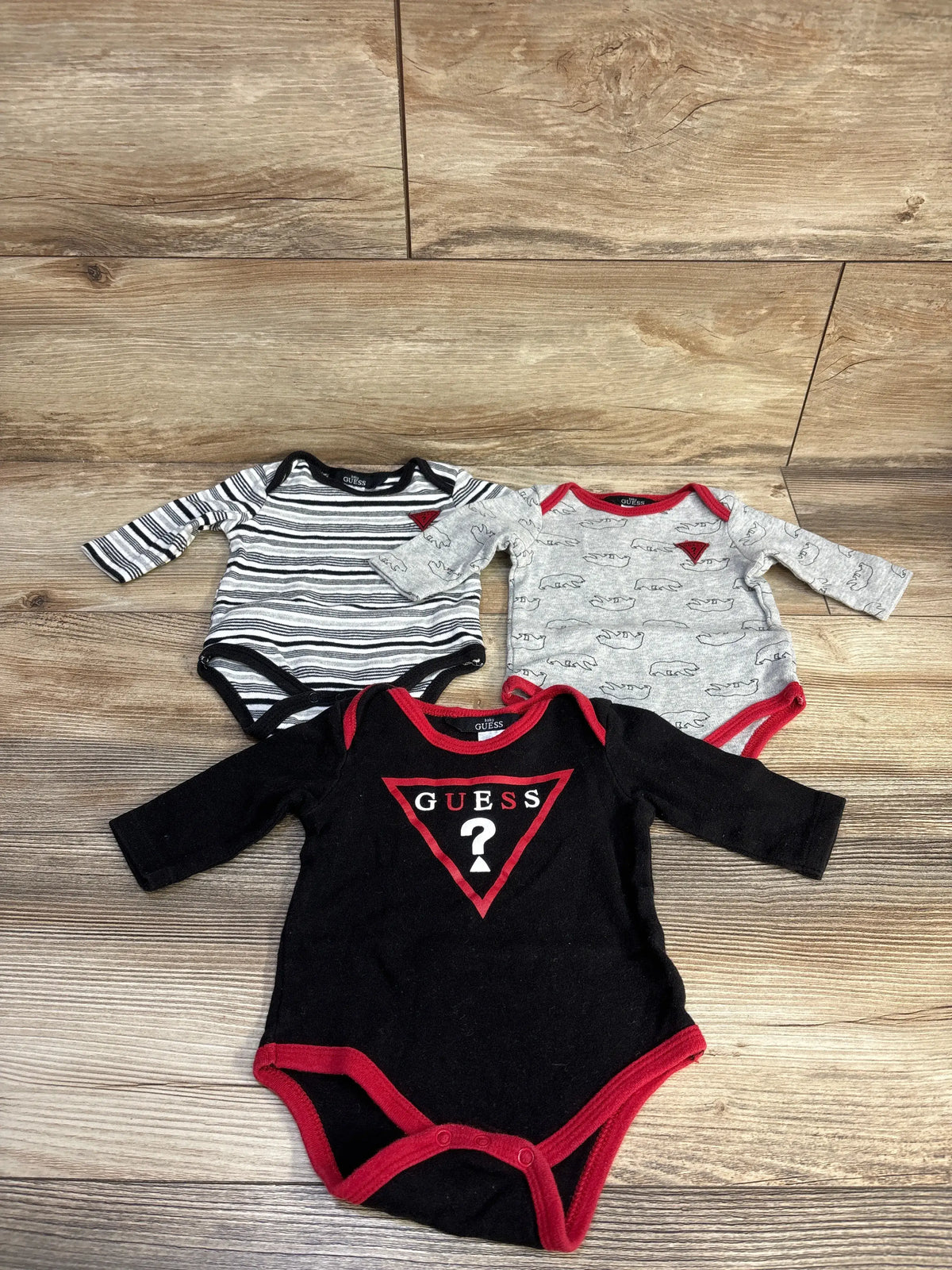 Front view of Baby Guess three-piece bodysuit set showcasing striped, animal-print, and Guess-logo designs
