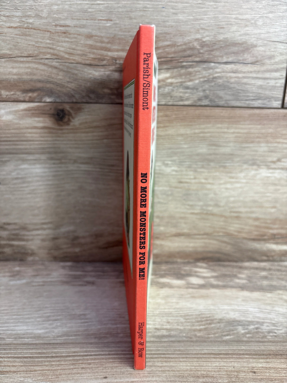 Spine of children's book No More Monsters For Me by Parish and Simont on wooden surface