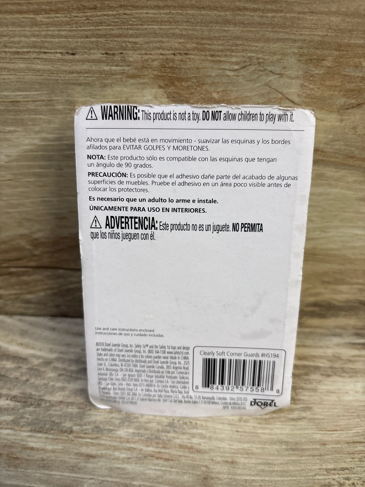 Rear of Safety 1st Clearly Soft Corner Guards 4-pack packaging showing warning text and barcode on a wooden surface