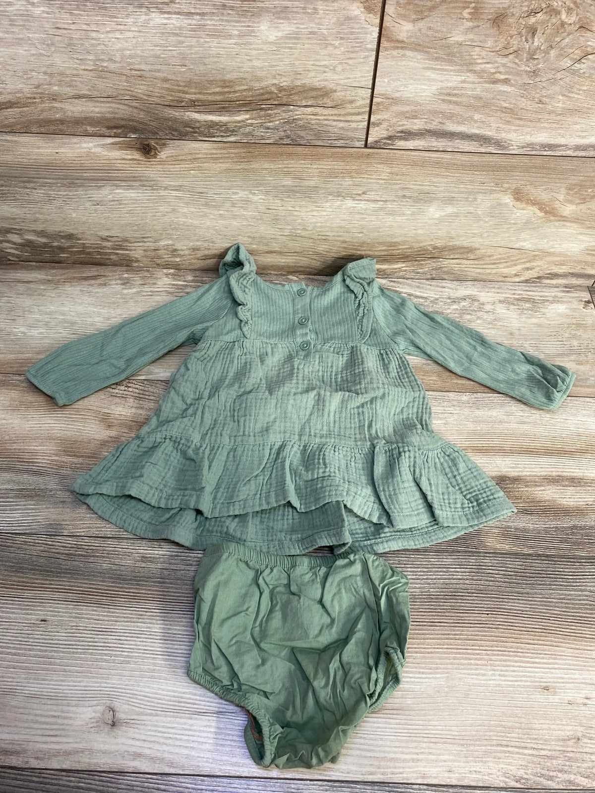 Sage green baby dress and bloomers set on wood background, long sleeve cotton outfit