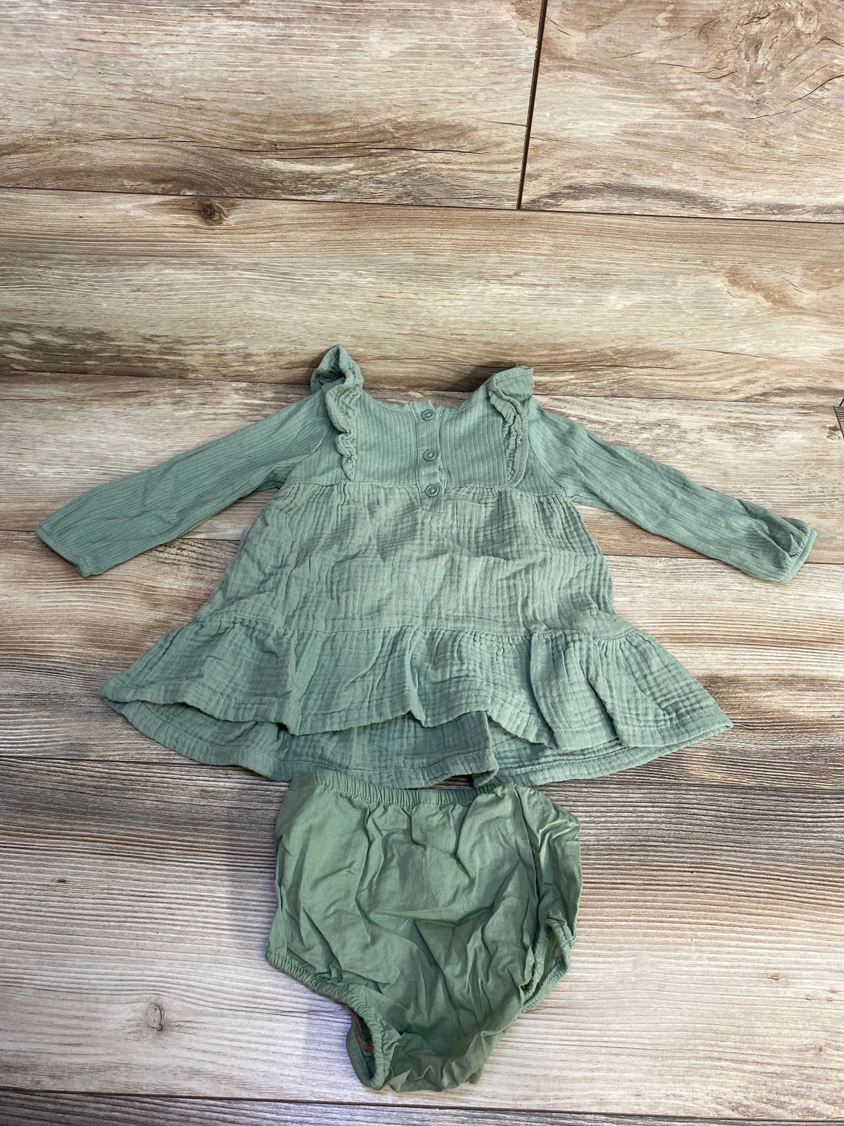 Sage green baby dress and bloomers set on wood background, long sleeve cotton outfit