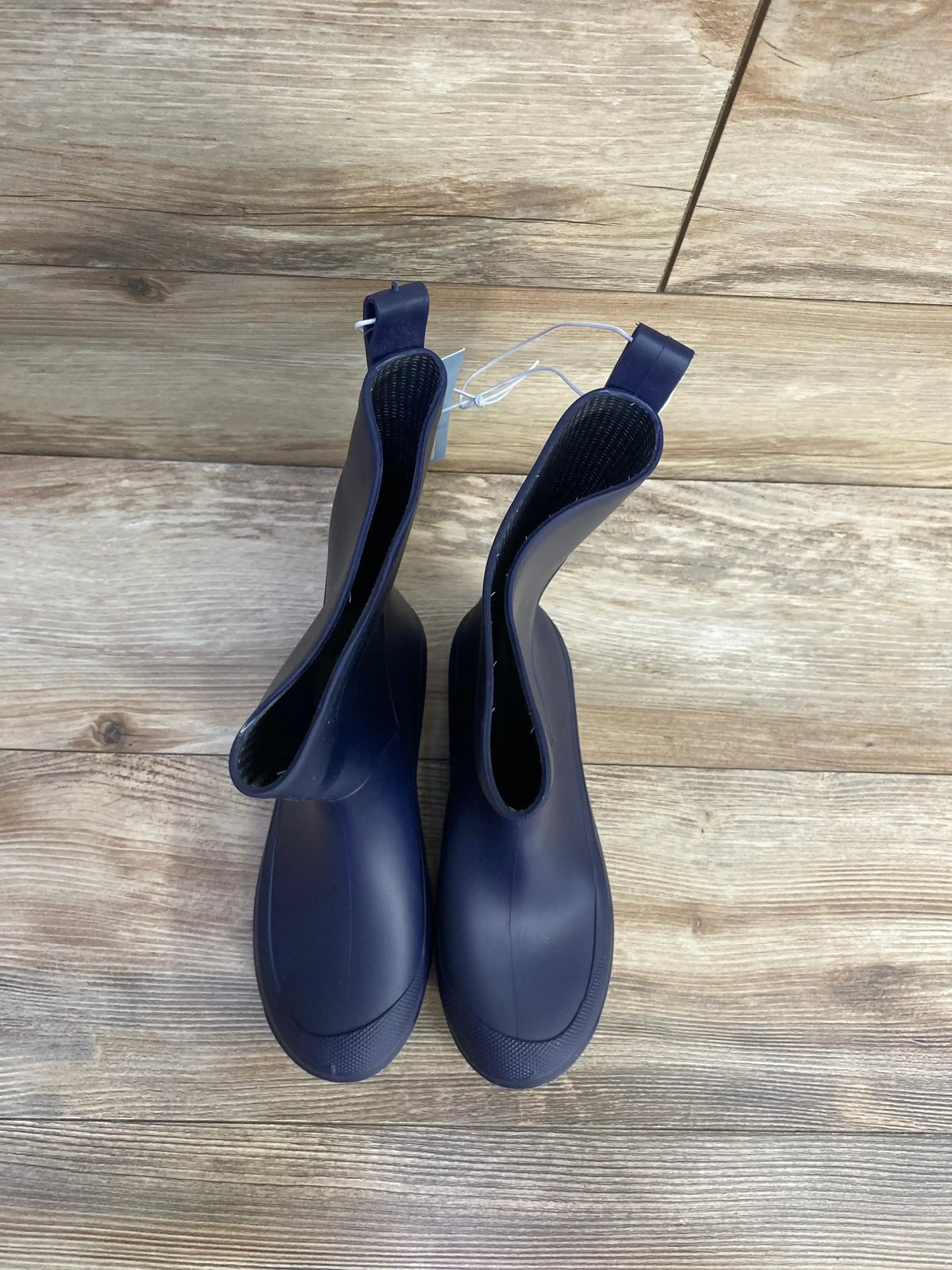 Top down view of Cat and Jack Andy navy slip on rain boots showing pull tabs and rubber upper on wood floor