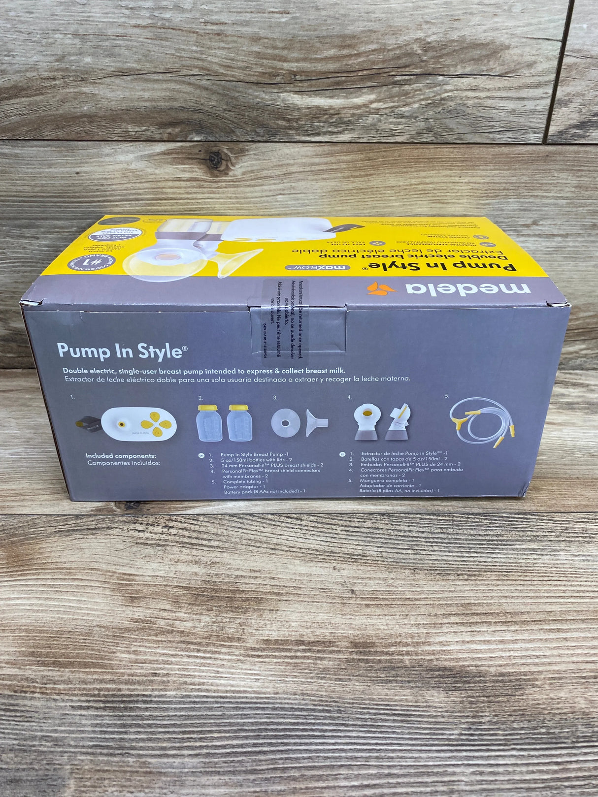 Front view of Medela Pump In Style boxed double electric breast pump showing pump, two bottles, tubing on wood background