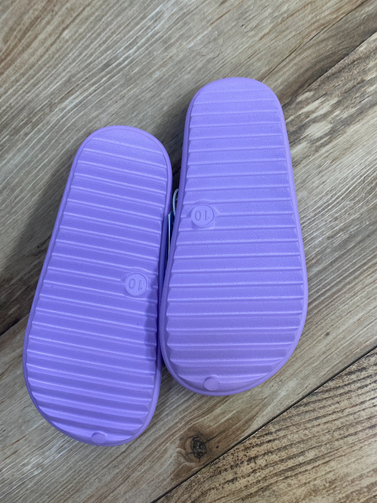 Bottom view of Cat and Jack purple toddler water shoes showcasing ribbed soles and size 10 marking on wood floor
