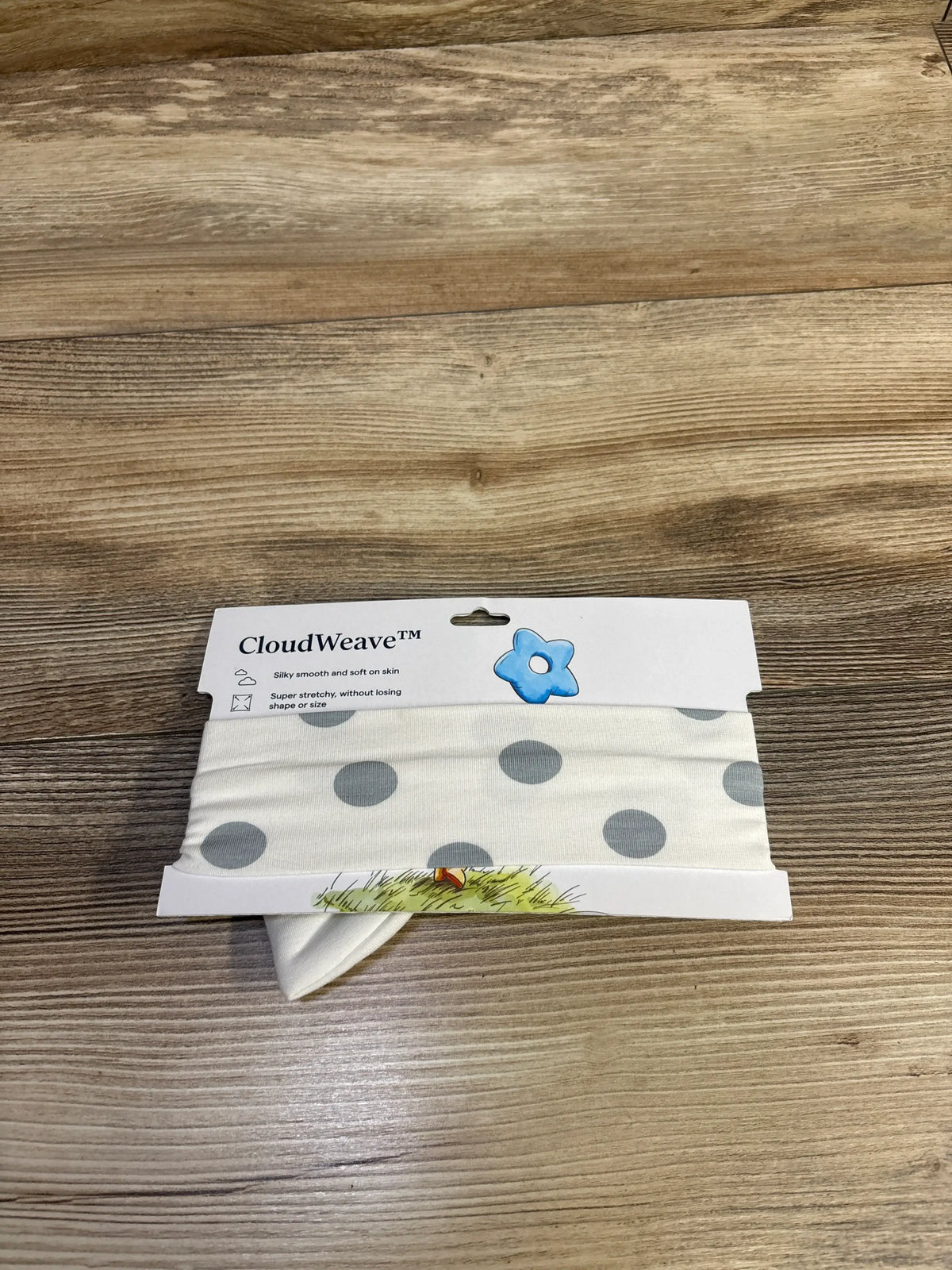 Front view of Larkspur bamboo polka dot bow headband in small size on CloudWeave packaging with wooden background