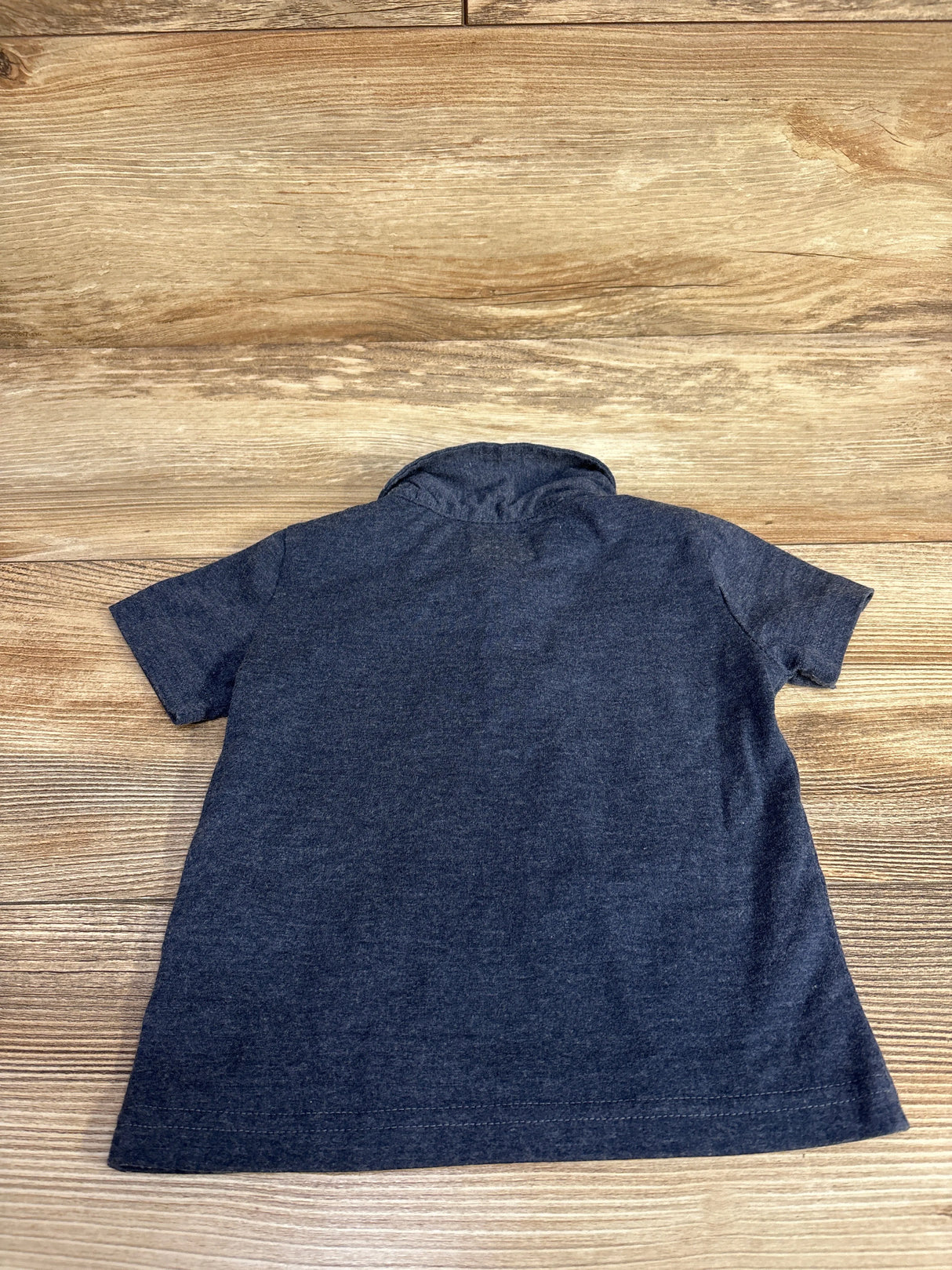 Dark gray short-sleeve polo shirt laid flat on a wooden surface