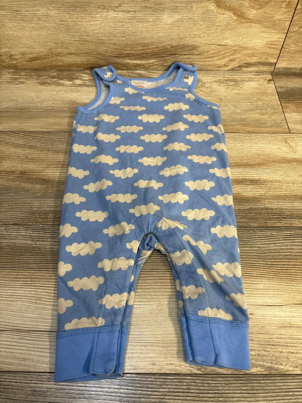 Blue baby romper with white cloud pattern on wooden floor