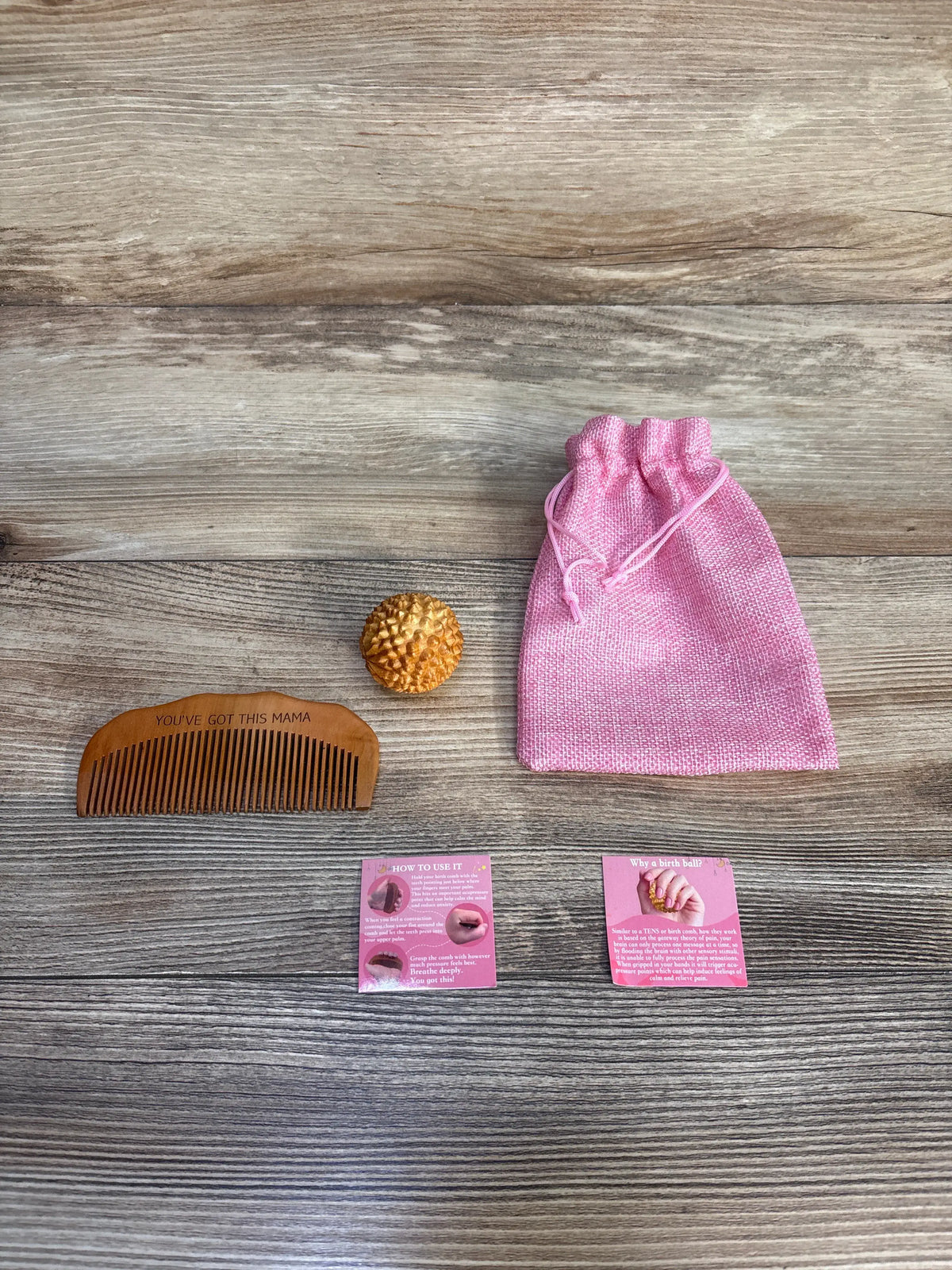 Top view of FSYQUAST 2pc Birth Comb + Acupressure Massage Ball Set with wooden comb, spiky ball, and pink bag