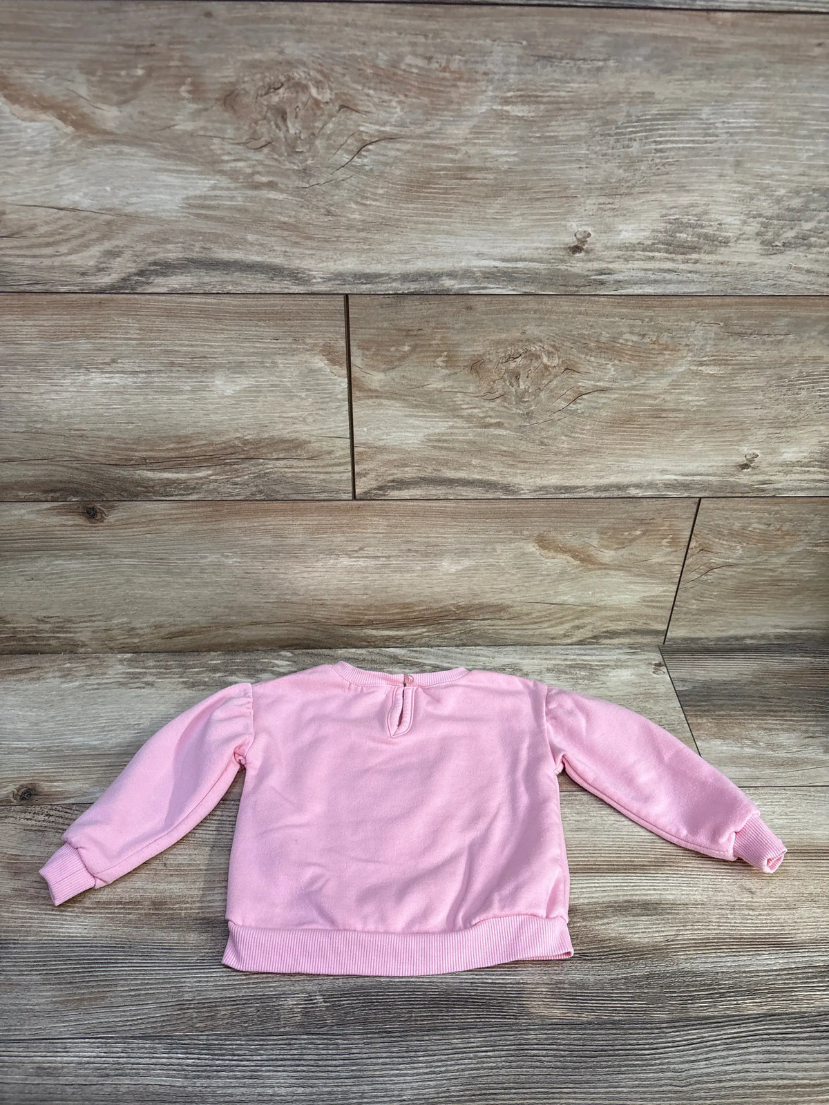 Flat lay of Btween bear sweatshirt in pink, size 18 months, showcasing long sleeves and ribbed trim