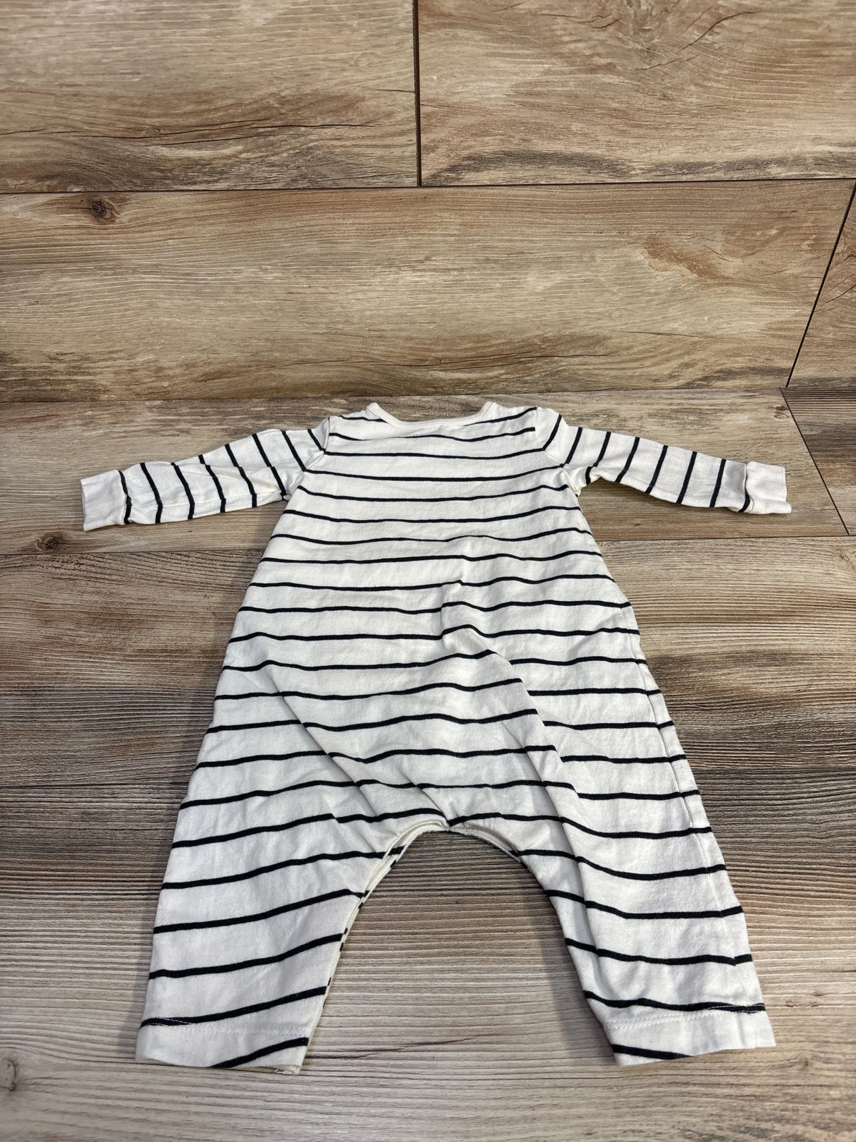 White baby romper with black horizontal stripes on wood floor