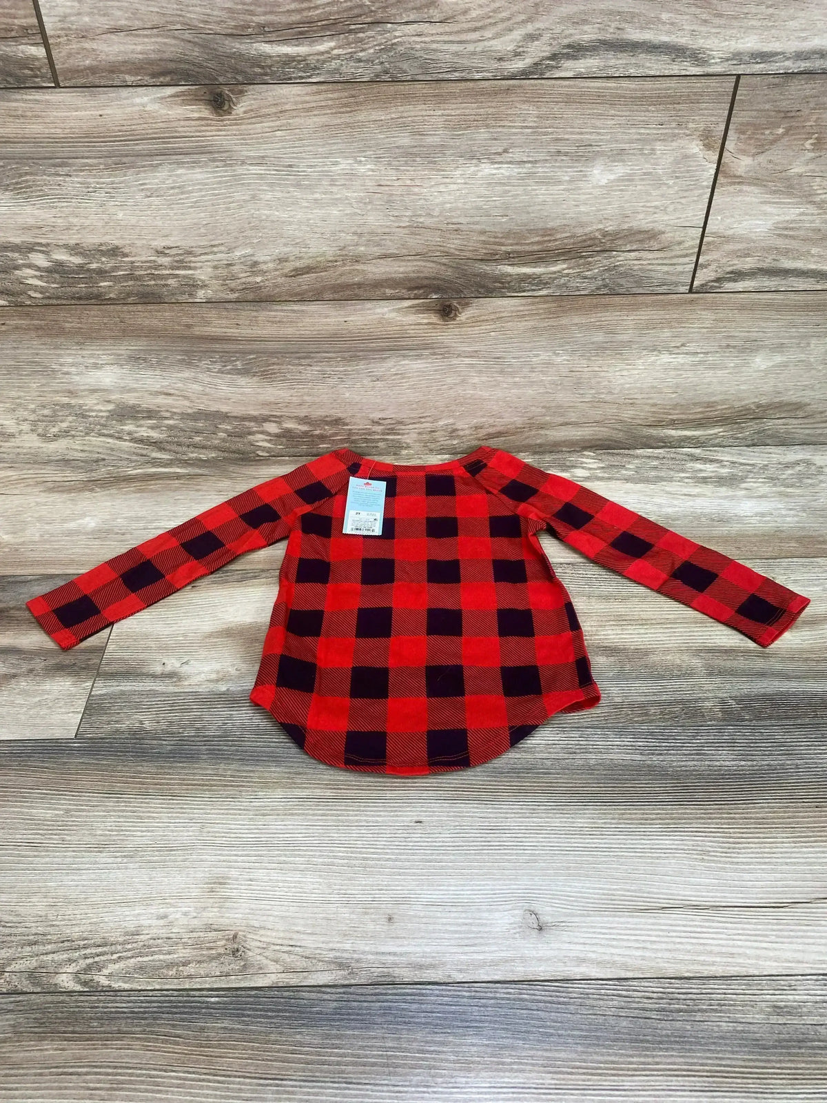 Flat lay of Cat and Jack red and black buffalo check long-sleeve shirt with curved hem and size tag on wood background