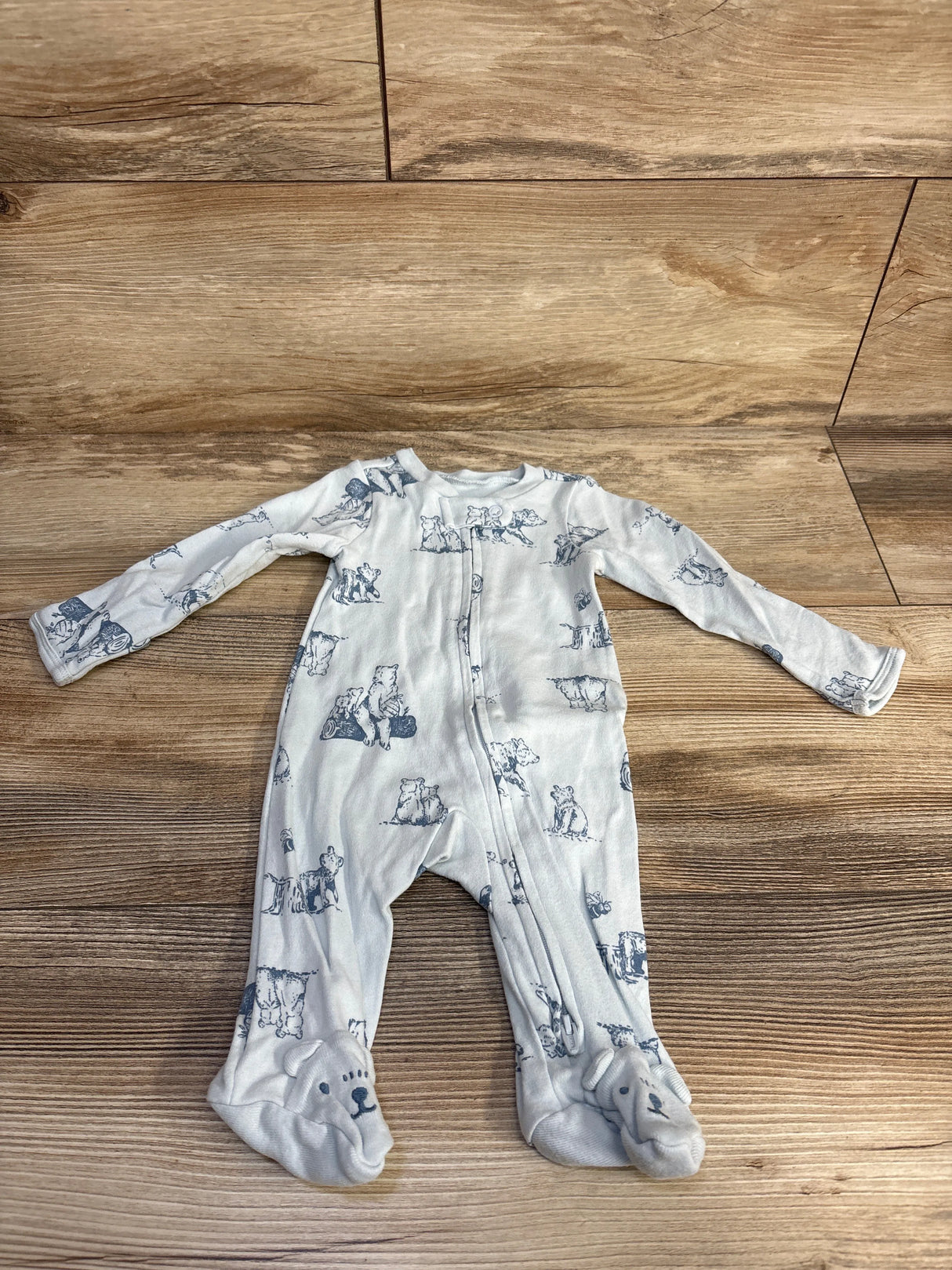 White baby sleeper with bear print and bear face footies on wooden floor