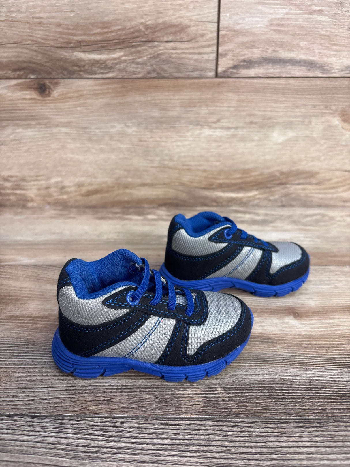 Blue and gray toddler sneakers with laces on wooden floor background
