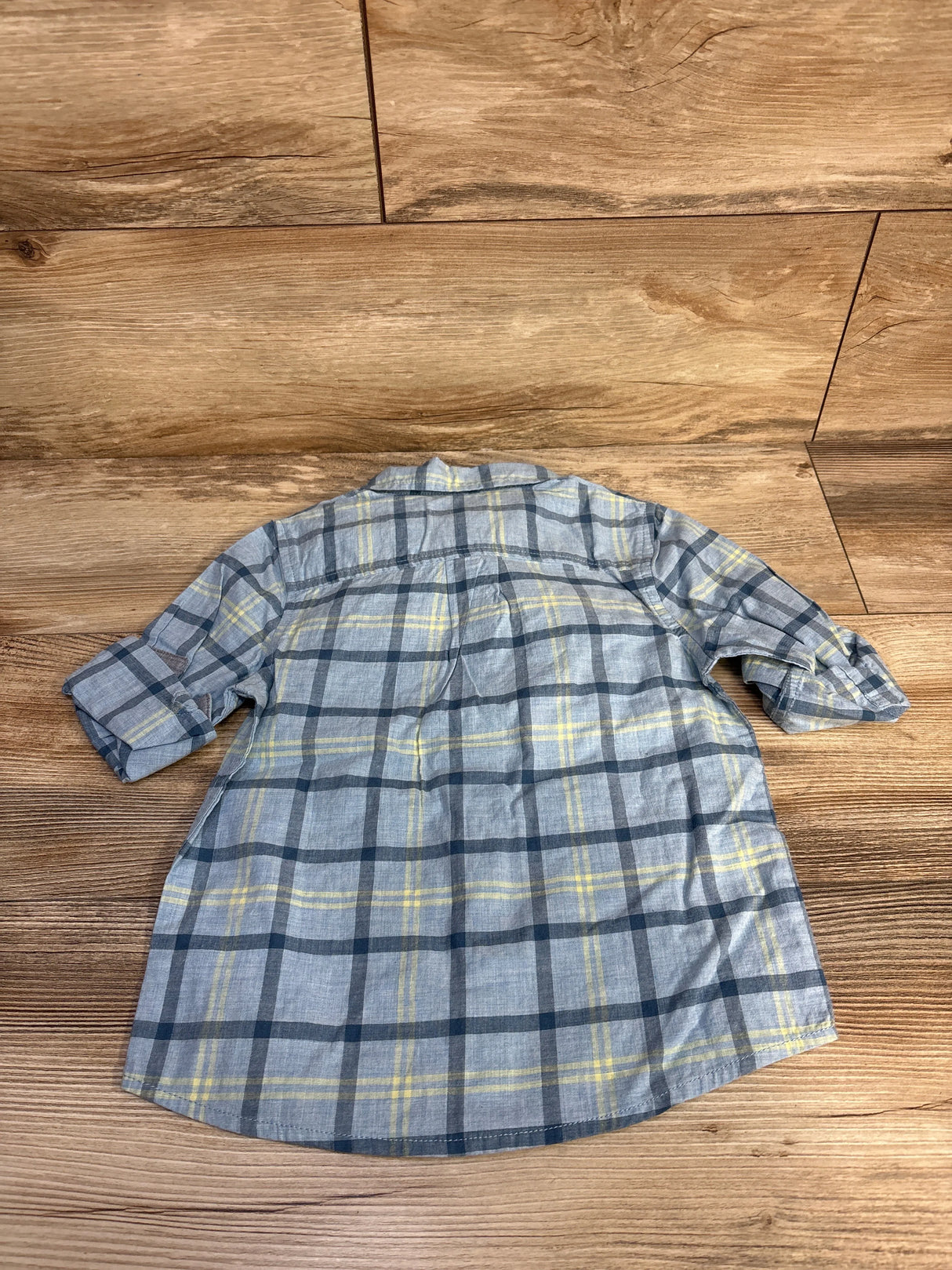 Gray and yellow plaid button-up shirt on wood floor, kids long sleeve flannel top